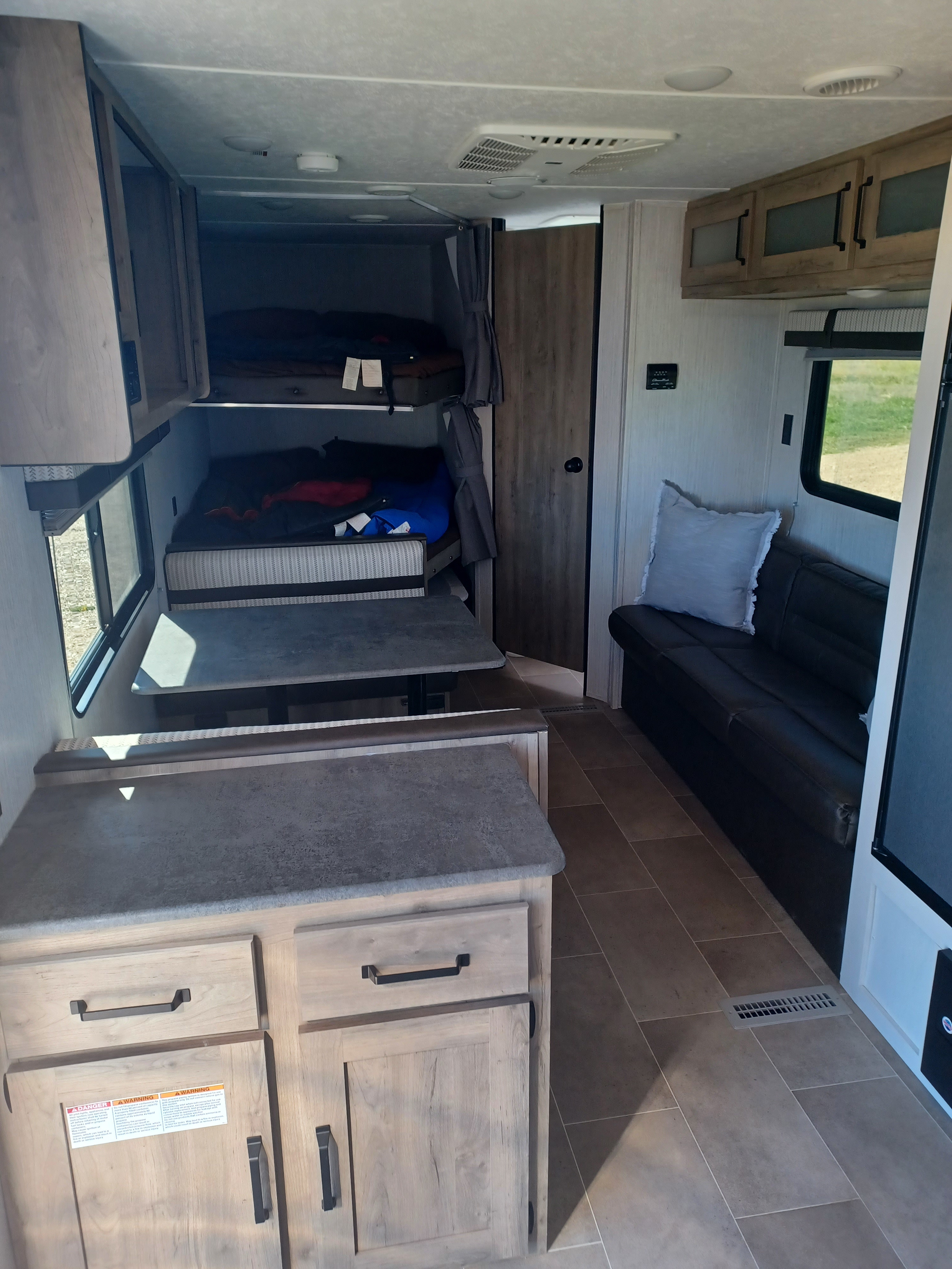 Modern RV rental interior with bunk beds, dining area, and living space visible inside the camper.. Forest River Palomino Puma XLE Lite 2021