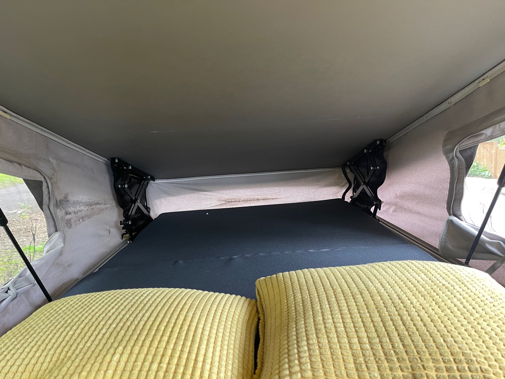 Cozy pop-top bed in an RV rental, with a dark mattress and yellow pillows. Ready for travel.. Winnebago Eurovan Camper Eurovan Camper 1999