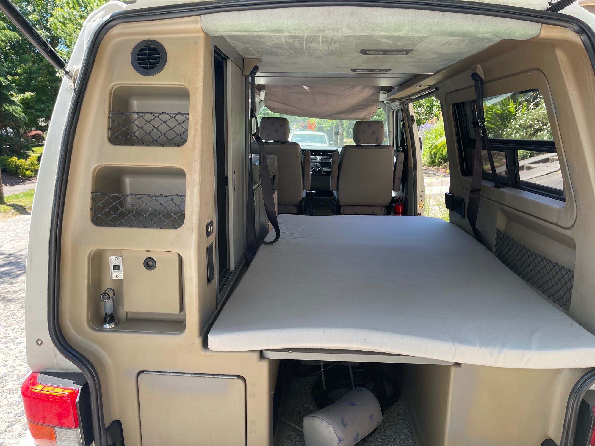 Inside this RV rental: a comfy bed, integrated storage with nets, and a built-in water sprayer, perfect for travel.. Winnebago Eurovan Camper Eurovan Camper 2001