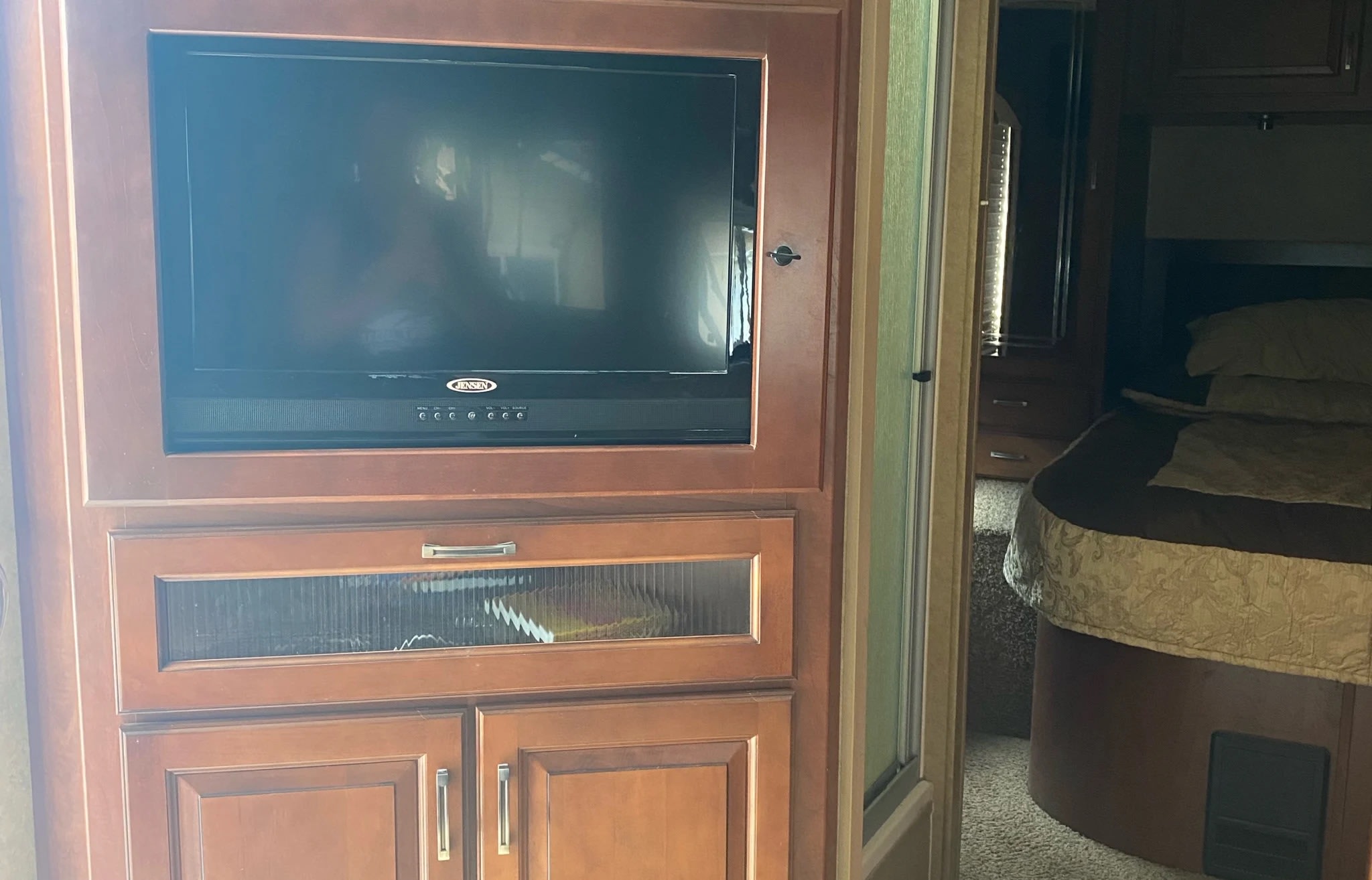 RV rental interior: Wooden entertainment center with TV & JENSEN system, leading to a cozy bedroom.. Jayco Greyhawk 2013
