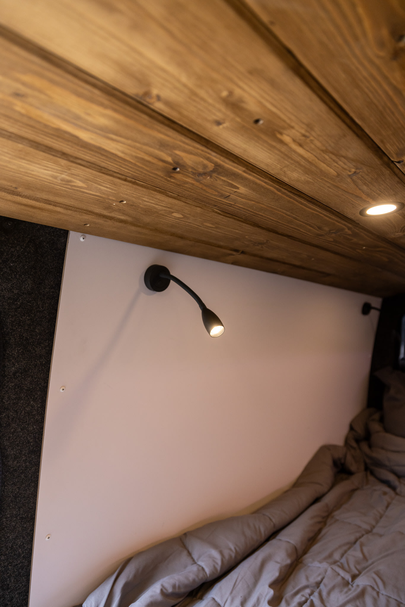 RV rental interior: A cozy bed area with a flexible reading light, sleek paneling, and warm wood ceiling.. Mercedes Sprinter 2500 2024