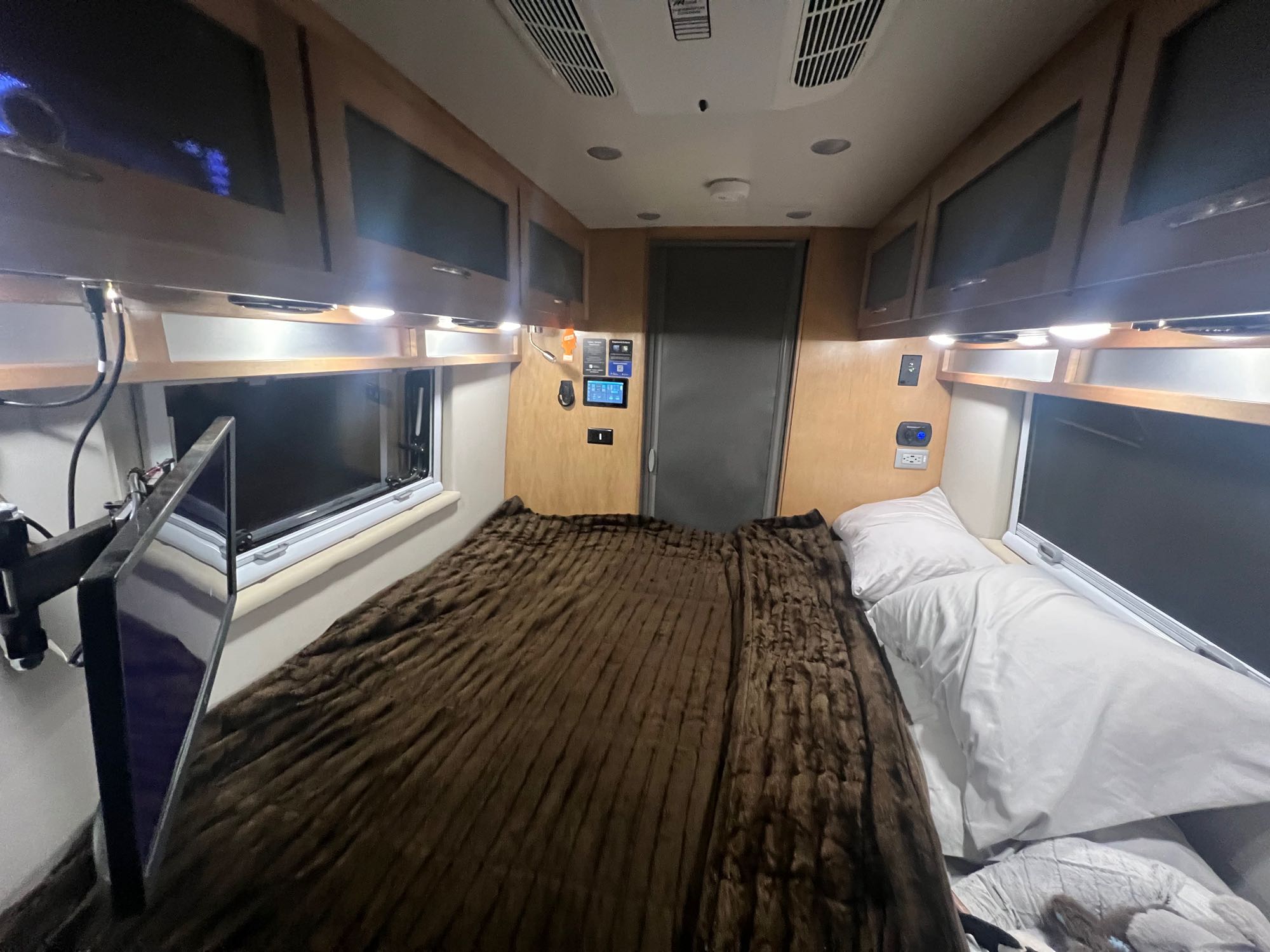 Cozy RV rental bedroom with large bed, wall-mounted TV, and overhead storage.. Forest River Coachmen Nova 2021