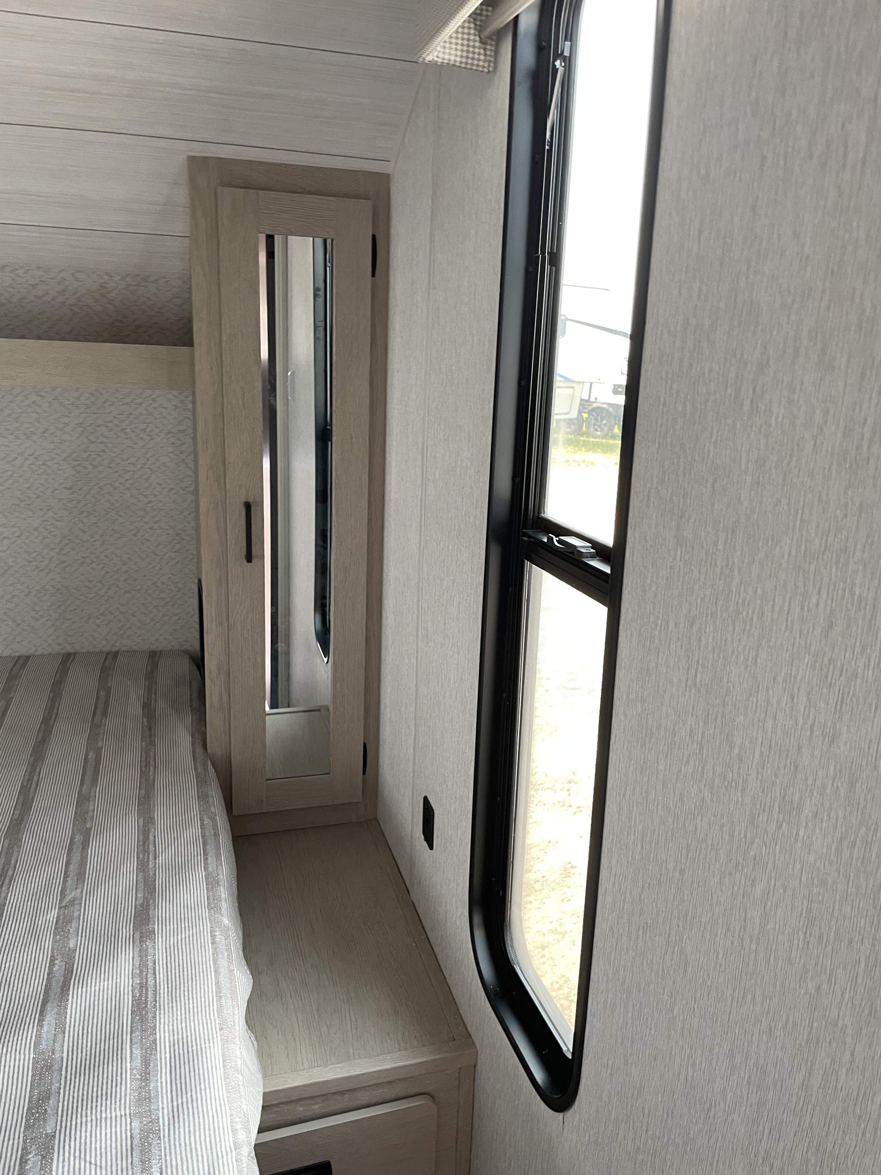 RV rental bedroom: light-colored walls, striped bed, mirrored cabinet, and tall window.. Salem 240BHXLX 2023