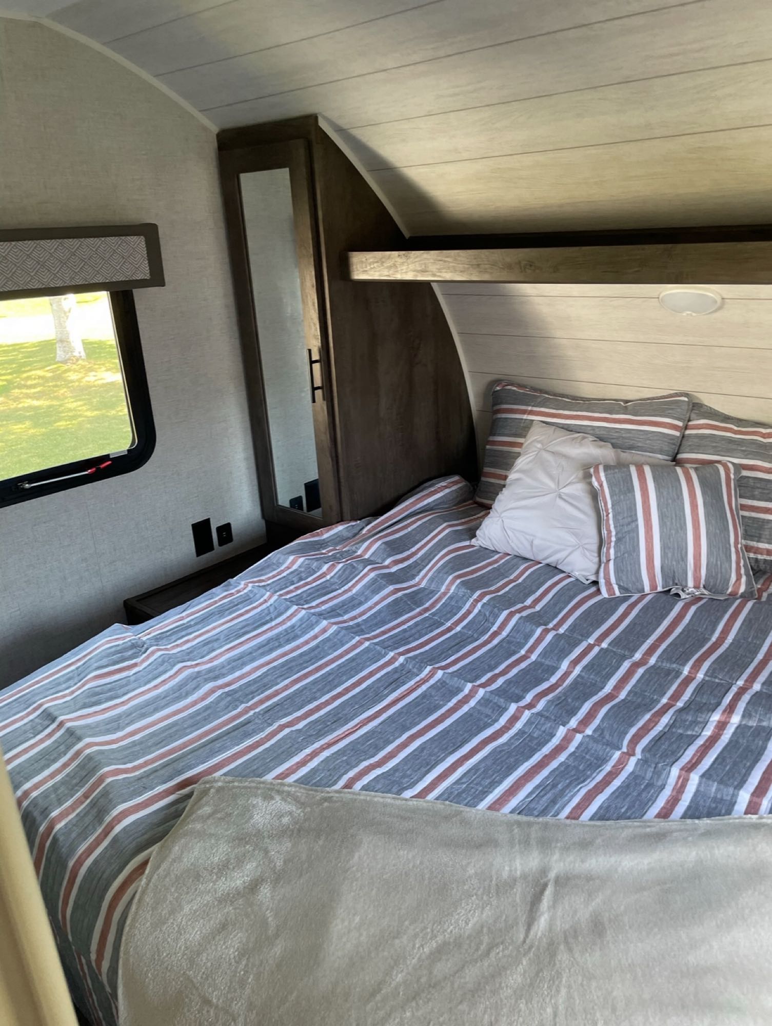 Cozy RV rental bedroom with striped bedding, window views, and modern amenities for comfortable travel.. Forest River Wildwood X-Lite 2020