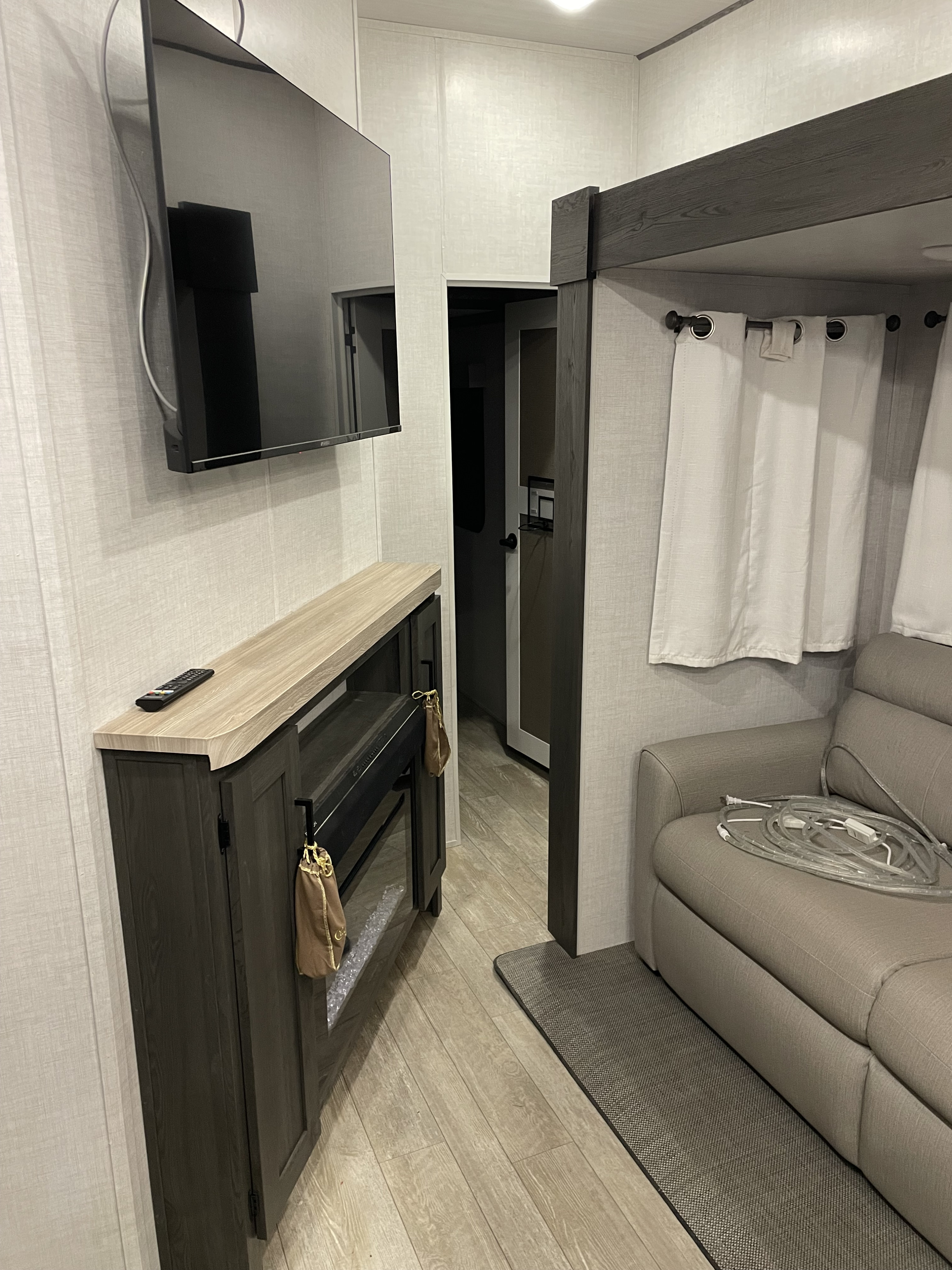 Inside a stylish **RV rental**: TV, fireplace, cozy sofa, and a hint of a bunk.. Forest River Impression 2024