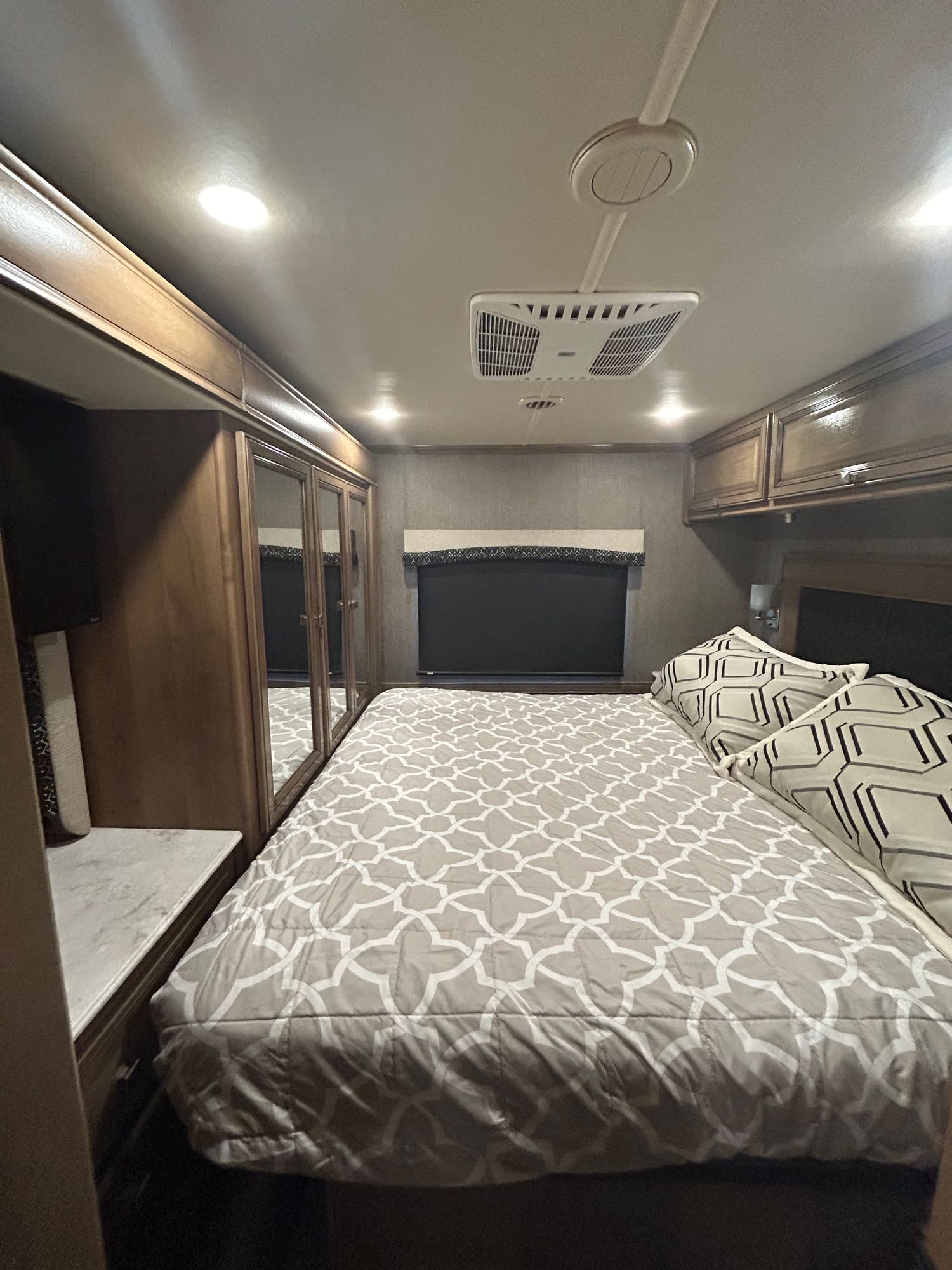 Step inside this modern RV rental bedroom featuring a comfy bed, mirrored wardrobe, and overhead storage for your road trip comfort.. Flair-Fleetwood Flair-Fleetwood Motorhome 2021