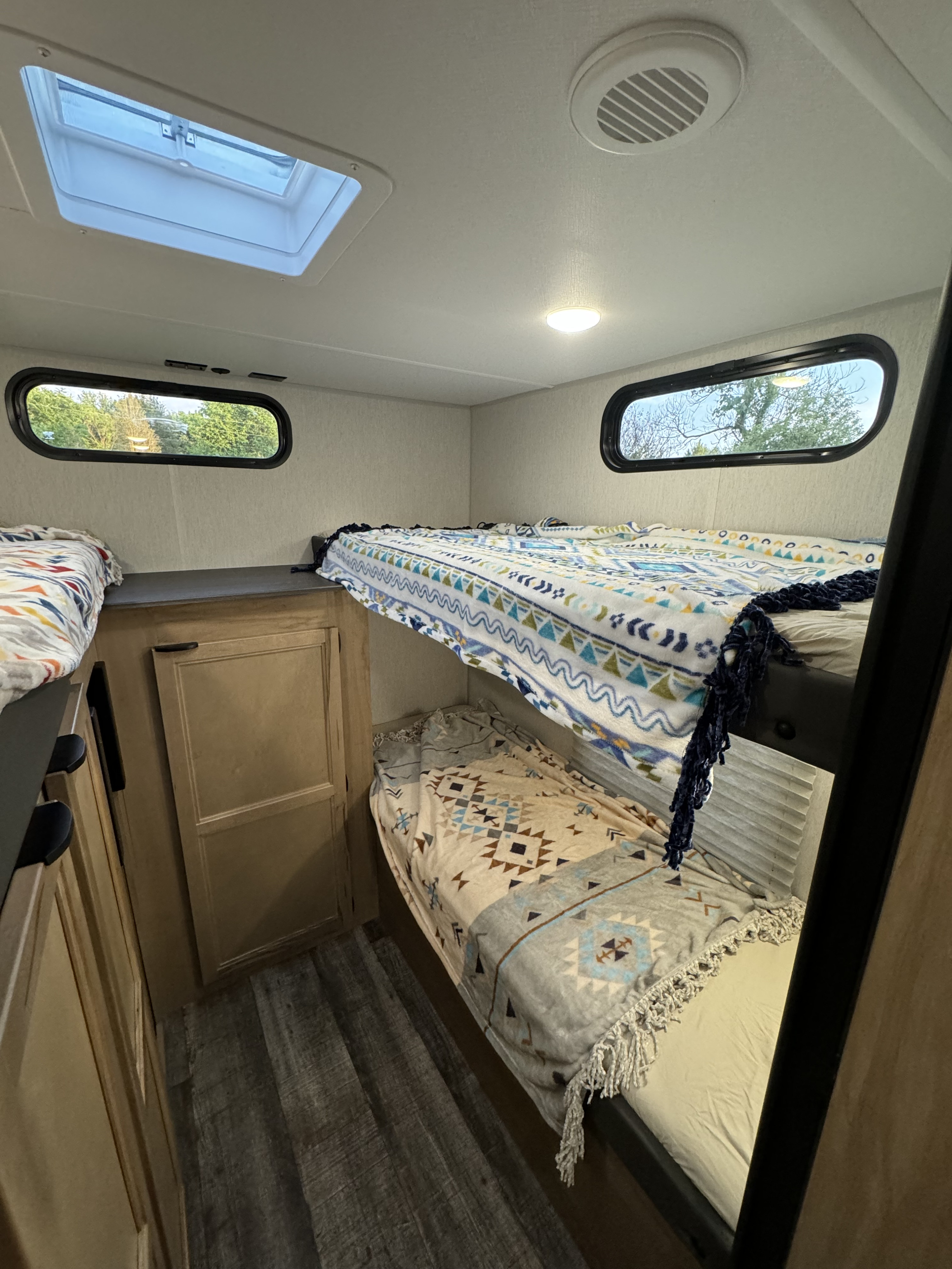 RV rental bunk bed area with three sleeping spaces, skylight, and windows, ready for a cozy trip.. Forest River Grey Wolf 29TE 2024