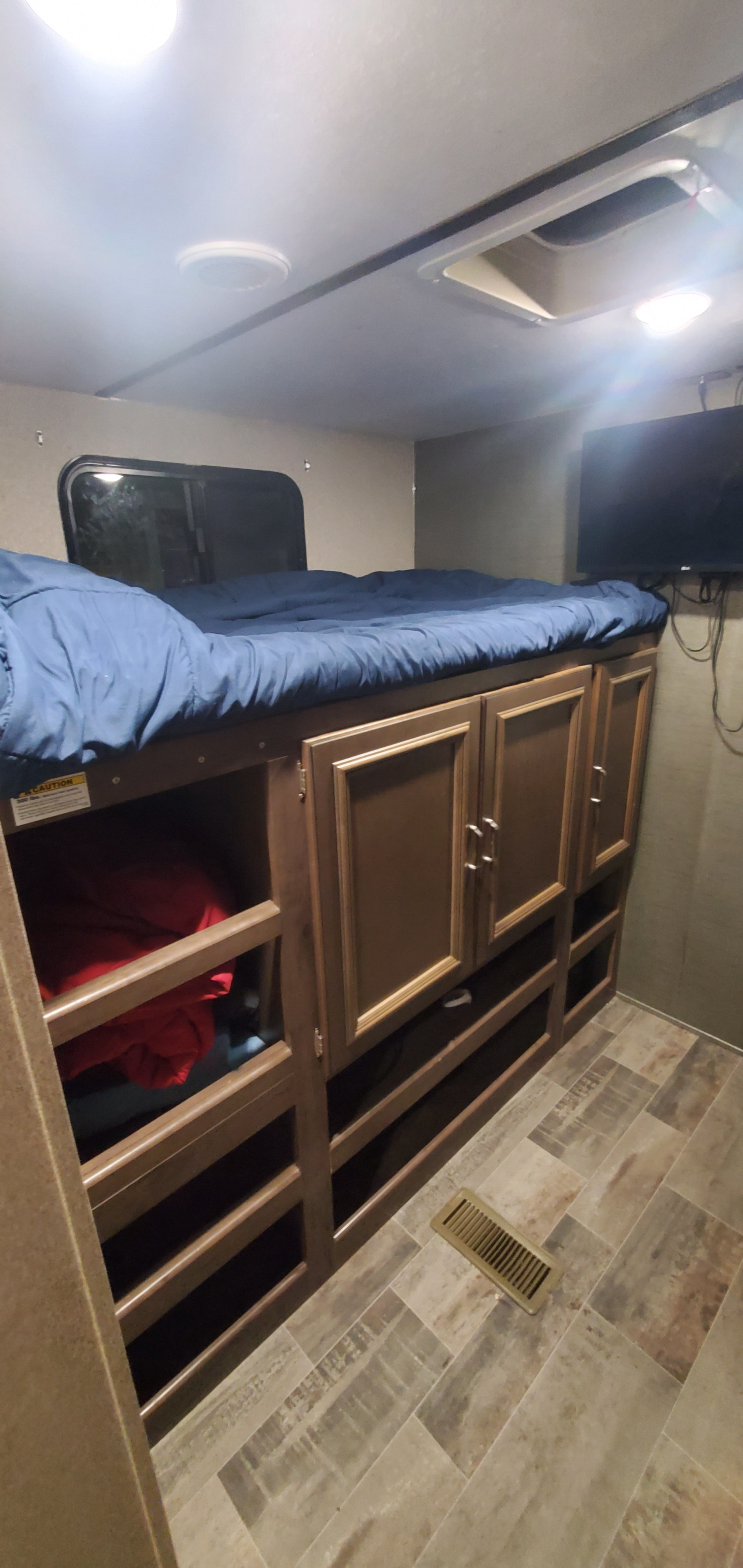 This RV rental features comfy bunk beds with blue bedding, ample built-in storage, a TV, and a window. Great for families.. Keystone RV Passport Grand Touring 2019