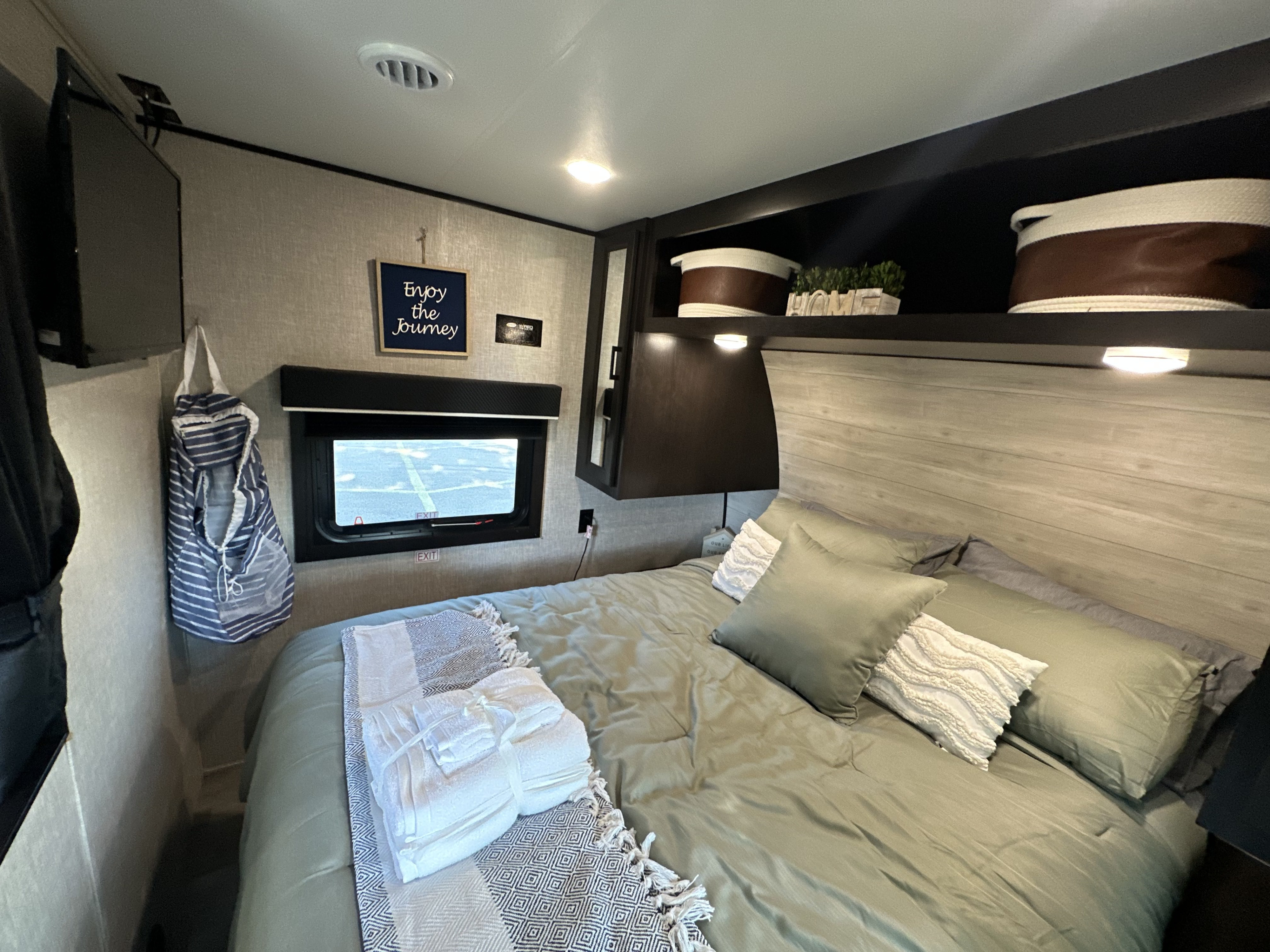 An RV rental's cozy bedroom, complete with a queen bed, TV, window, & homey decor.. Jayco Jay Flight 2023