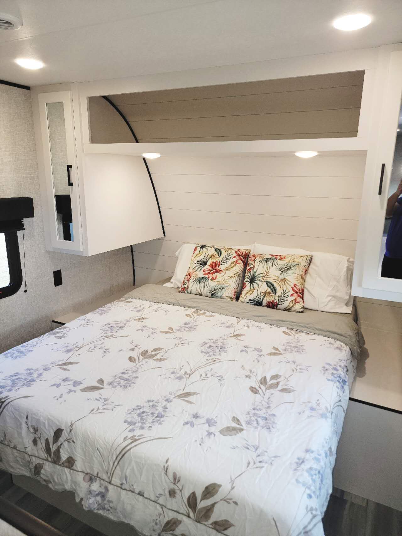 Cozy and compact RV rental bedroom with a floral bedspread, bright lights, and integrated storage.. Jayco Jay Flight SLX 2024