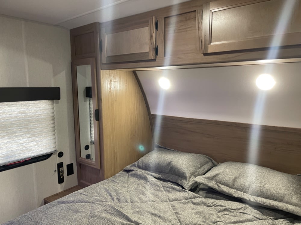 Cozy RV rental bedroom featuring a comfy bed, overhead cabinets, window, and bright reading lights for your adventures.. Forest River Grey Wolf 26 DBH 2024