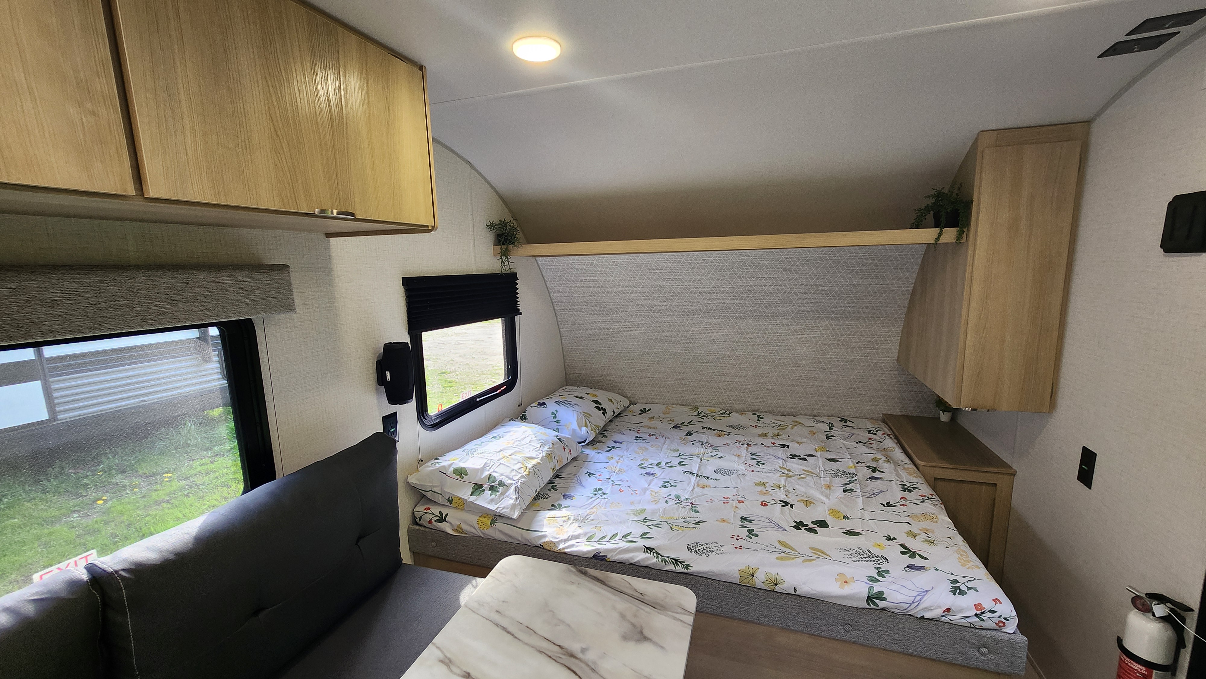 Inside this RV rental: a bright bedroom area with a floral bedspread, overhead cabinets, and a side dinette.. Forest River Salem FSX 174BHLE 2024