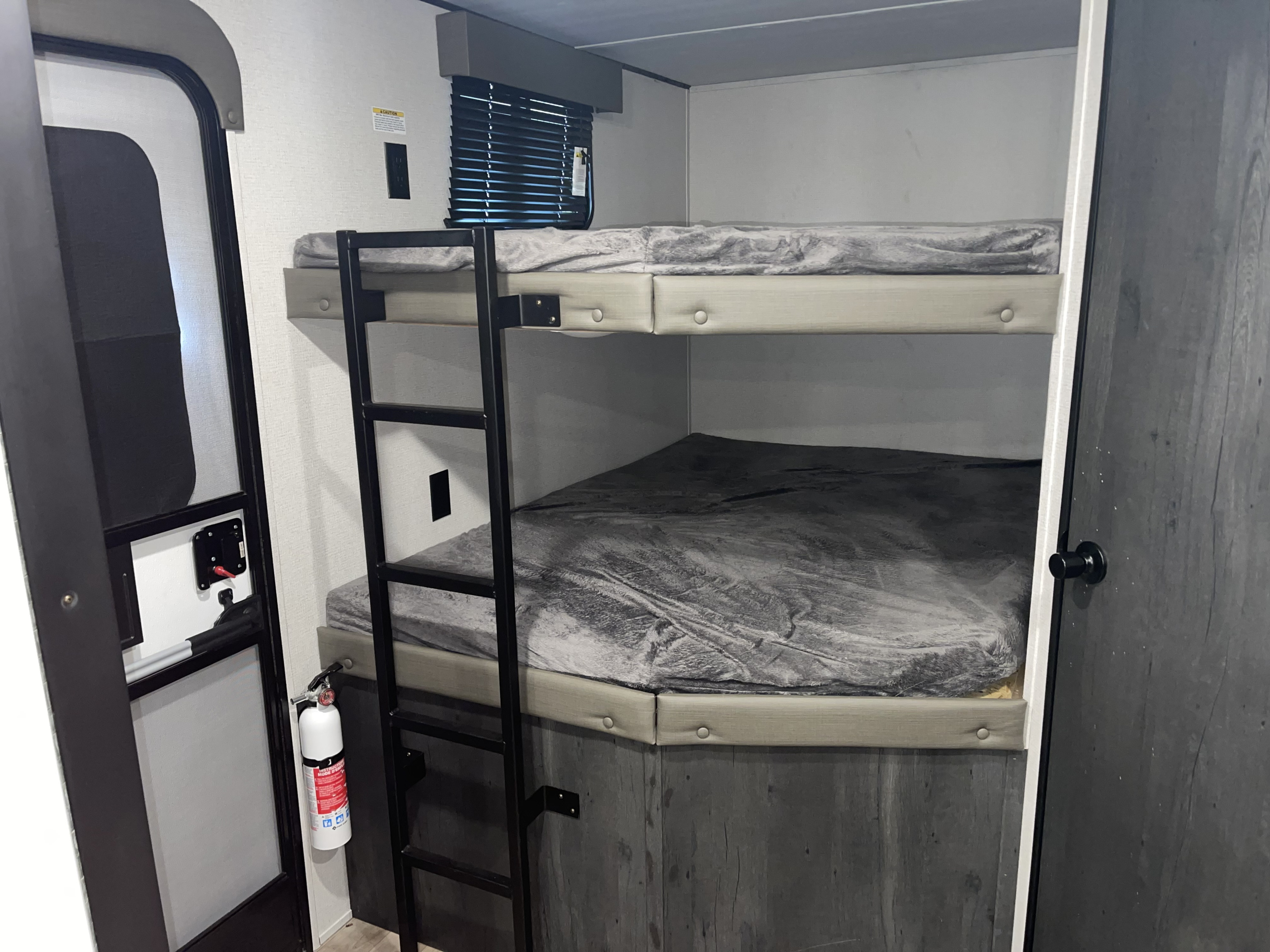RV rental interior featuring bunk beds, a ladder, and a safety fire extinguisher near the door for compact living.. Keystone RV Hideout 2022