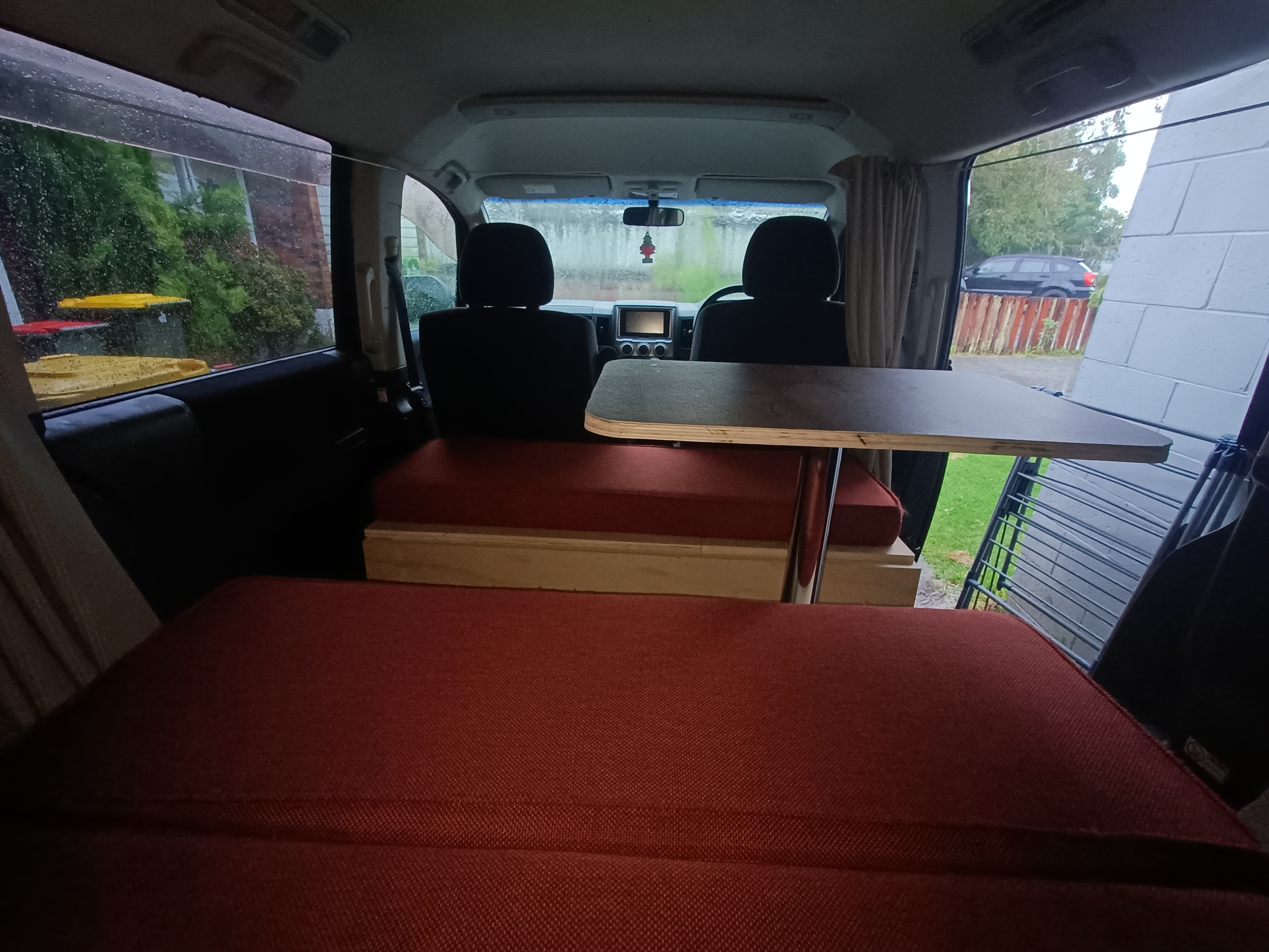 Inside a cozy rv rental camper van: custom bed, table, and seating. Ready for adventures, offering mobile living space.. Mitsubishi Delica 2007