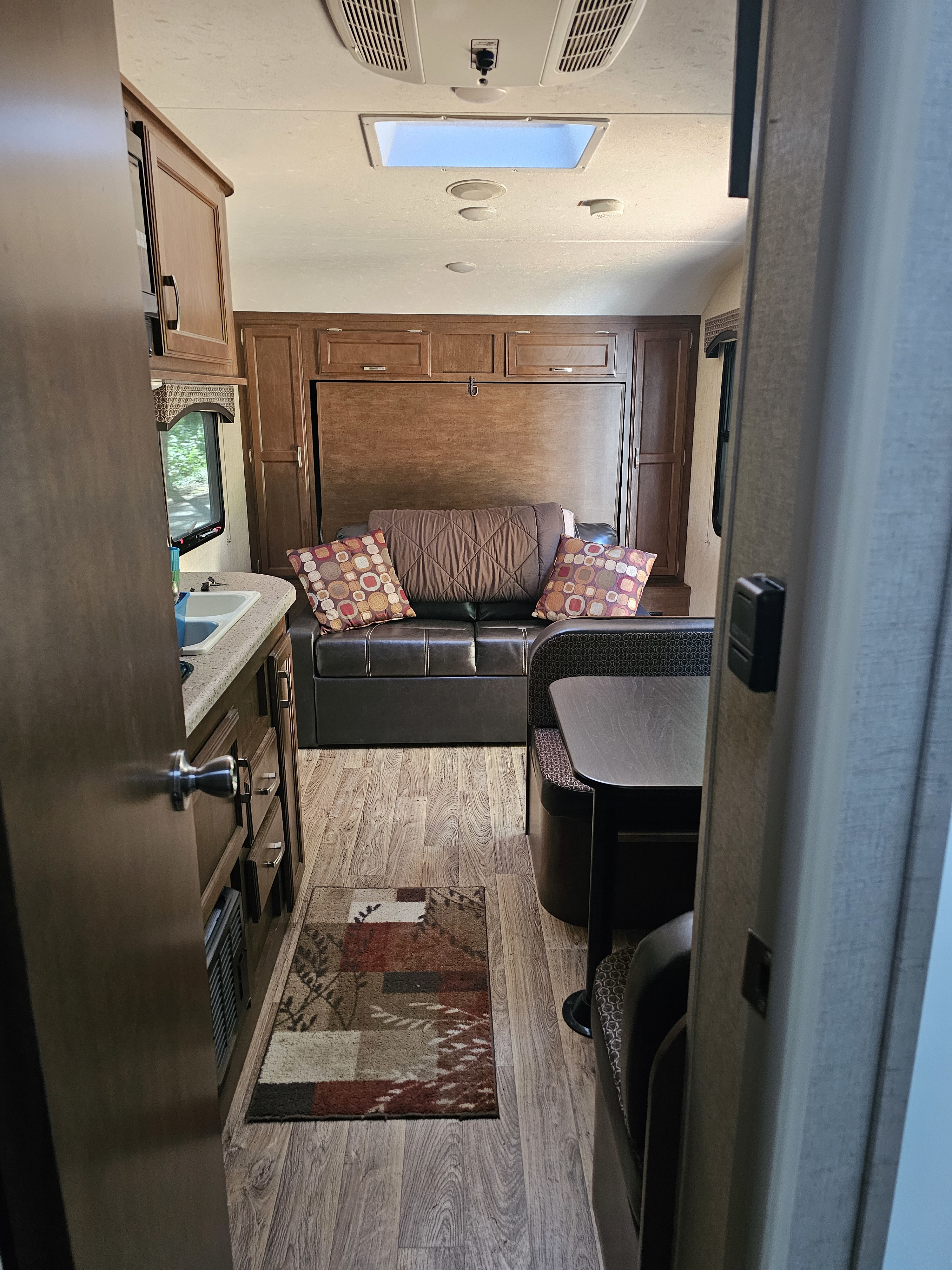 Cozy RV rental interior: view of the kitchen, living area with convertible couch/Murphy bed, and dinette.. Venture 190VRB 2019