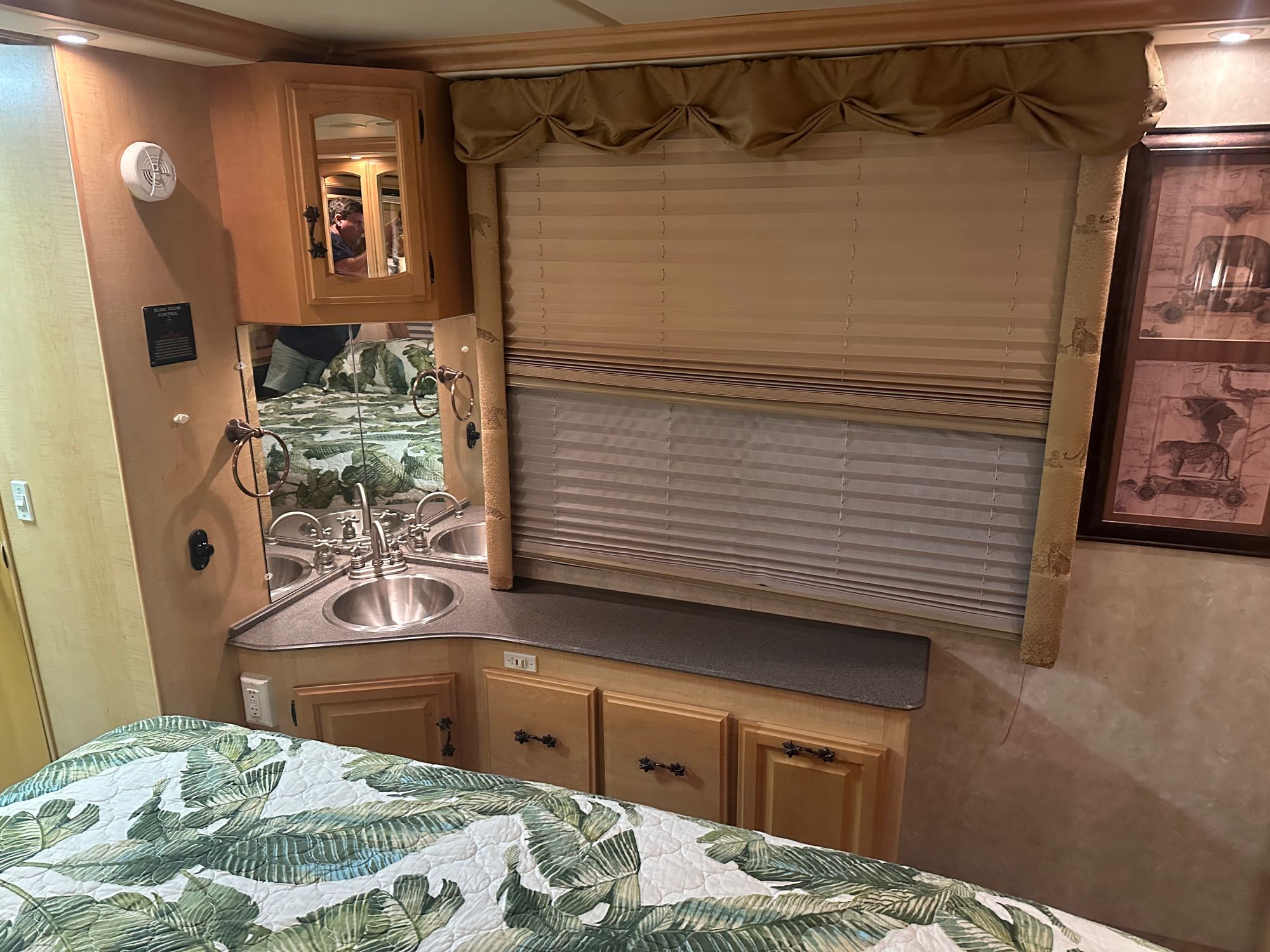 RV rental: a cozy bedroom area with a tropical-themed bed, integrated vanity, sink, mirror, and window with blinds.. Fleetwood Excursion 39s 2005