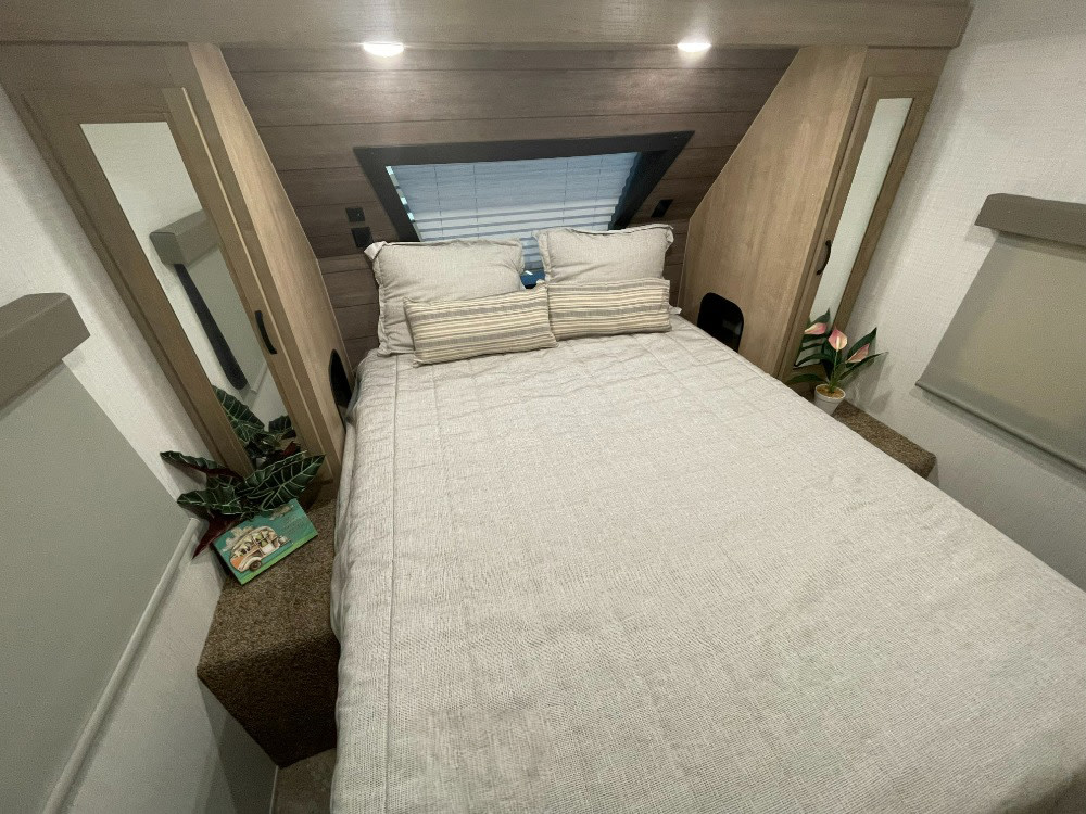 Cozy RV rental bedroom with a neatly made bed, ideal for comfortable travel. Features small plants & compact design.. Forest River Solaire 2023