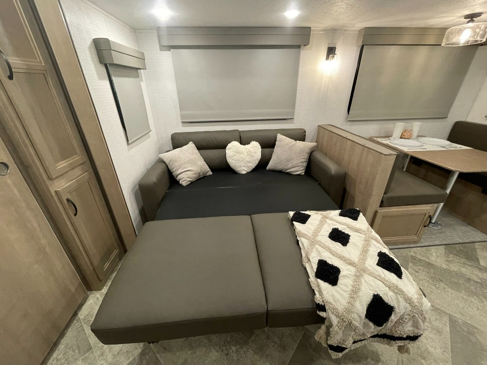Cozy RV rental interior showcasing a convertible sofa bed, dinette, and modern cabinetry, ideal for travel.. Forest River Solaire 2023