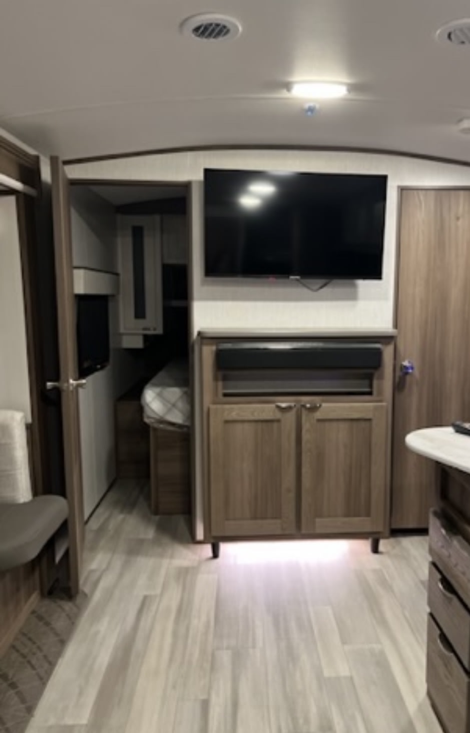 RV rental interior showcasing a cozy living space with a TV, cabinetry, and a glimpse of the sleeping area. Ideal for travel.. Cruiser RV MPG 2023