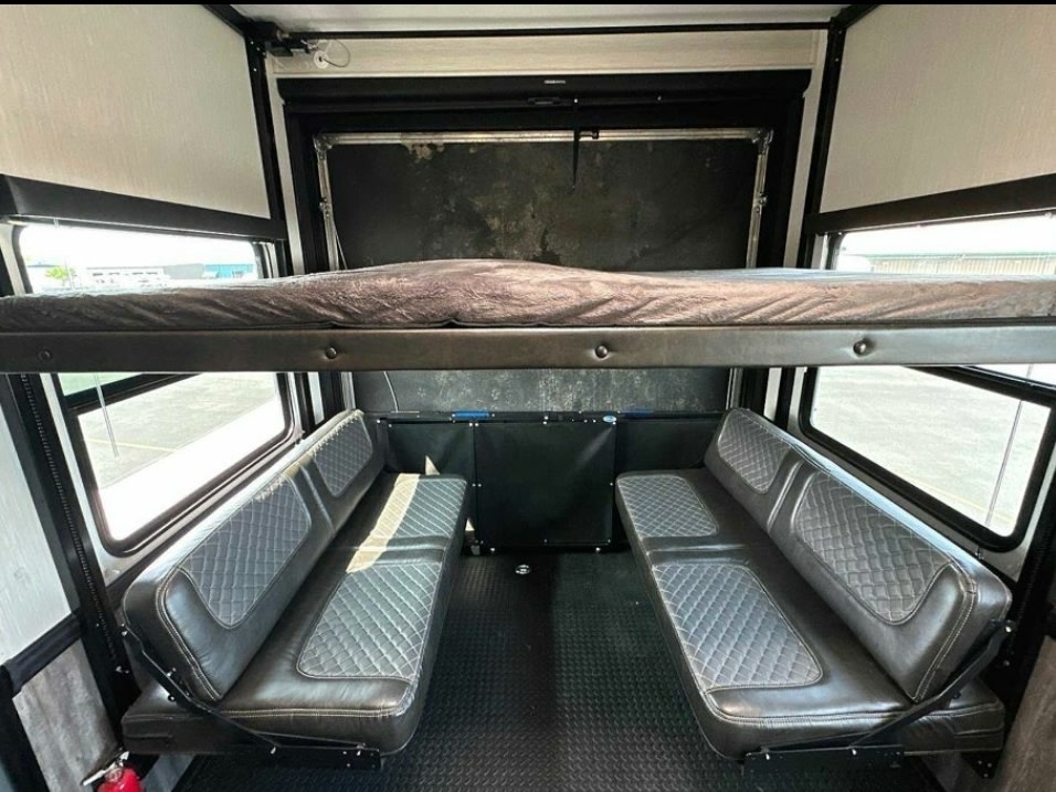 Spacious RV rental interior featuring a drop-down bunk bed and two quilted benches, ideal for versatile living.. Heartland Cyclone 2022