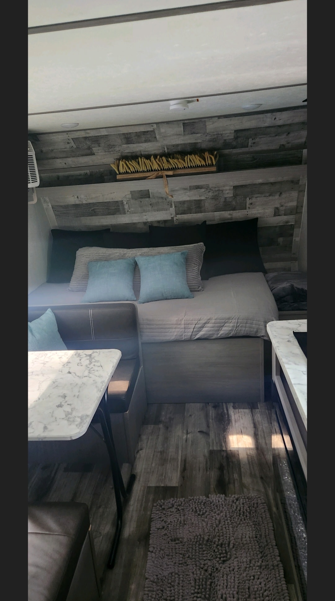 This RV rental shows a cozy interior with a bed, dinette, and rustic wood-paneled walls.. Dutchmen Coleman Lantern 2023