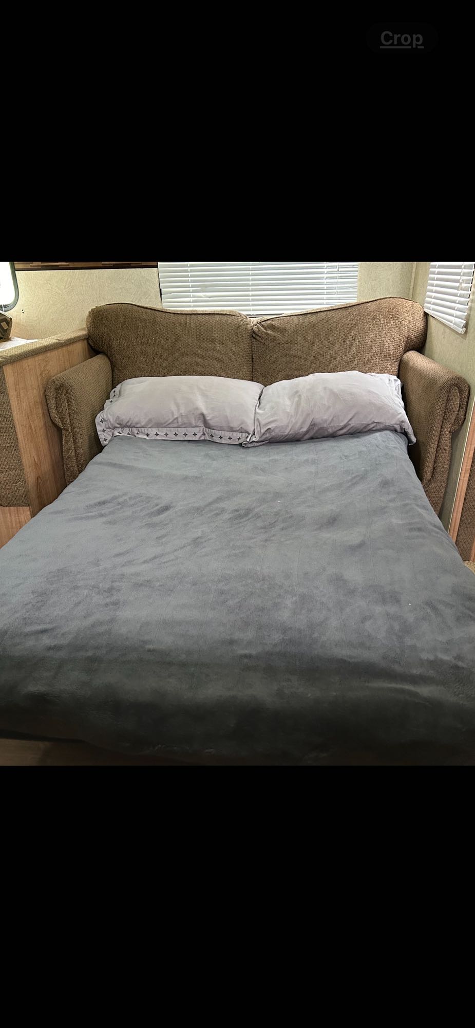 RV rental: Couch converted to a bed with grey bedding & pillows. Blinds on windows. A versatile sleeping solution inside.. Skyline Weekender 2012