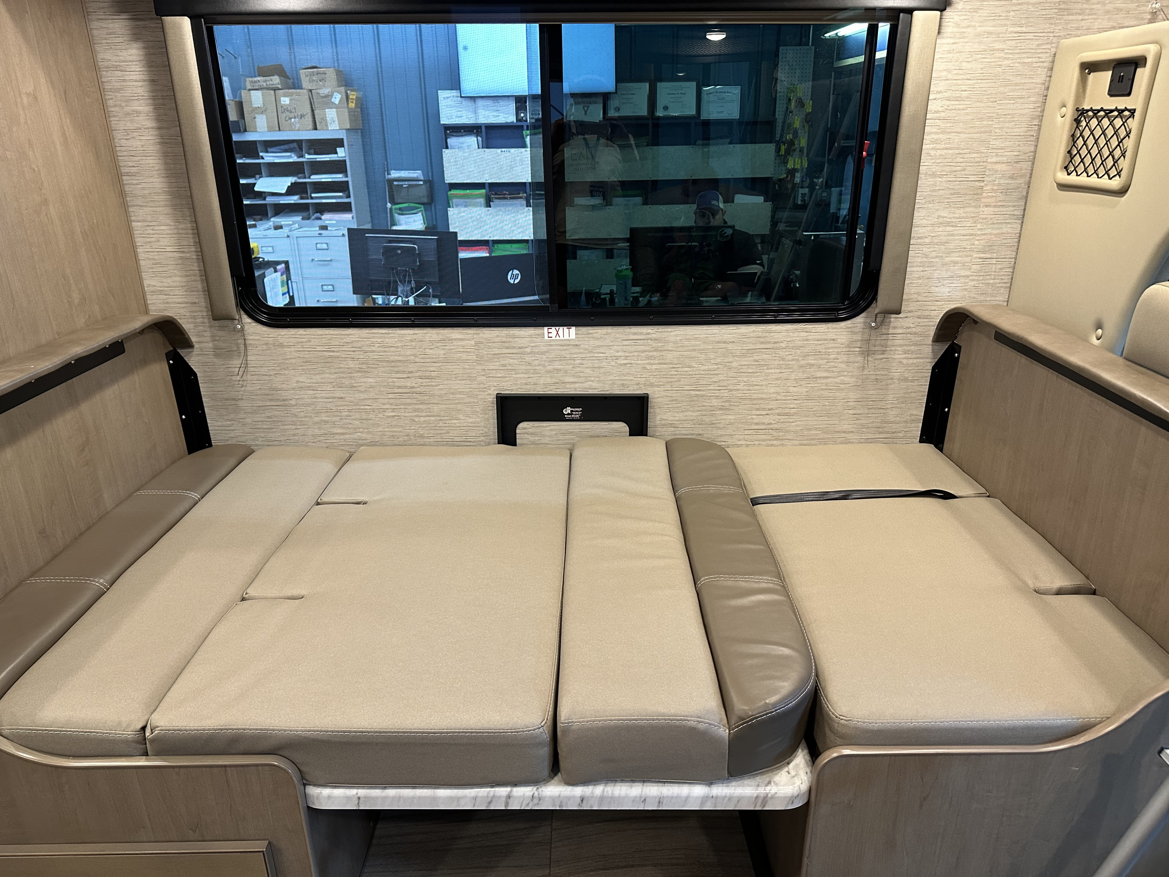 Experience comfort in this RV rental. The versatile dinette seating converts to a bed, visible with light upholstery and wood trim.. Thor Coleman 2021