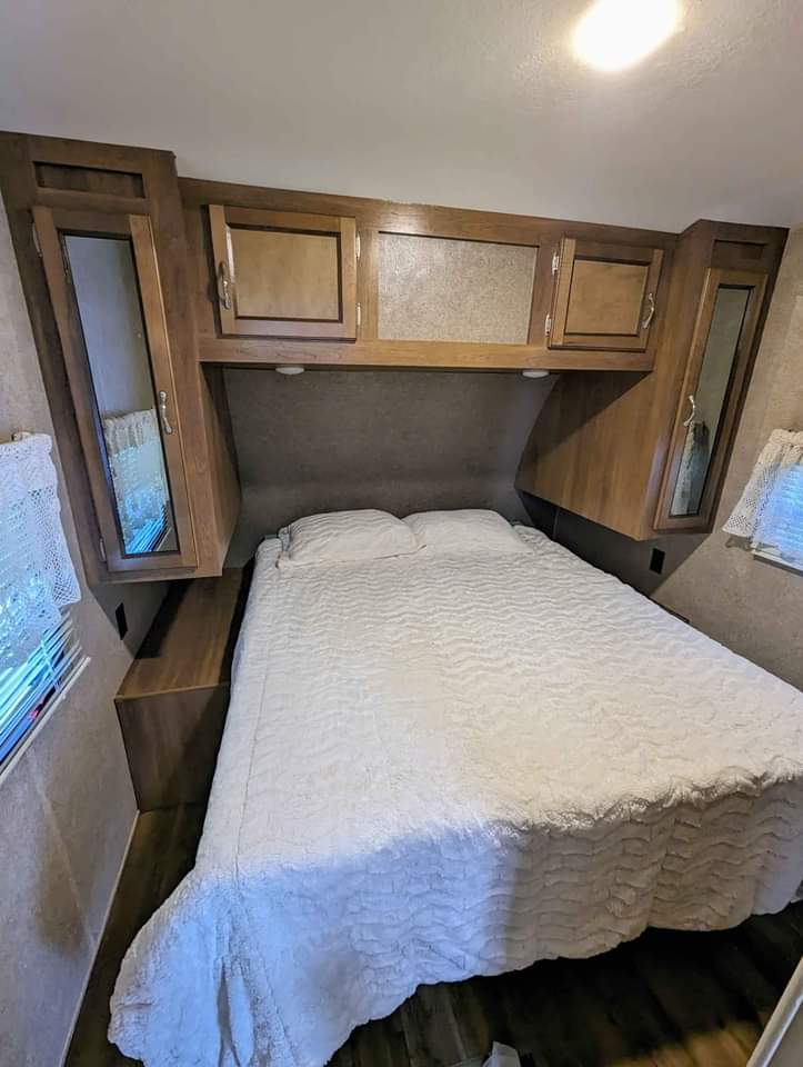 Cozy RV rental bedroom with white bedding, overhead storage, and mirrored cabinets for comfortable travel.. Coachmen M-283 DDS- 32' 2017