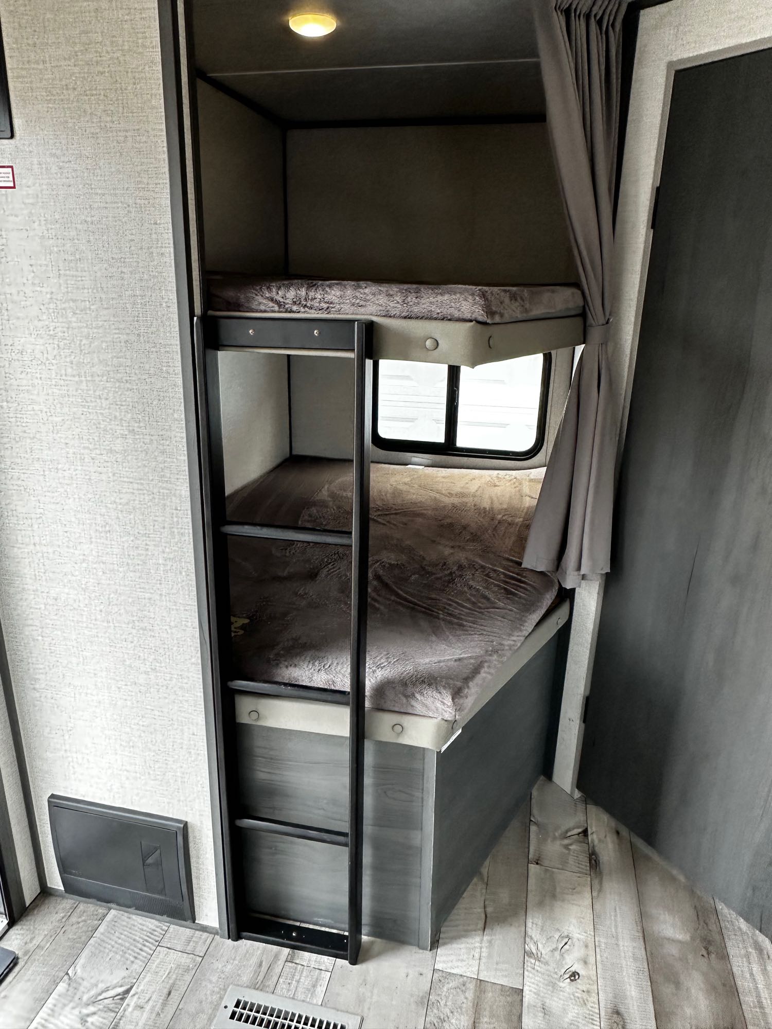 RV rental sleeping area featuring two cozy bunk beds with ladder, window, and curtains.. Aspen Trail Aspen Trail Trailer 2022