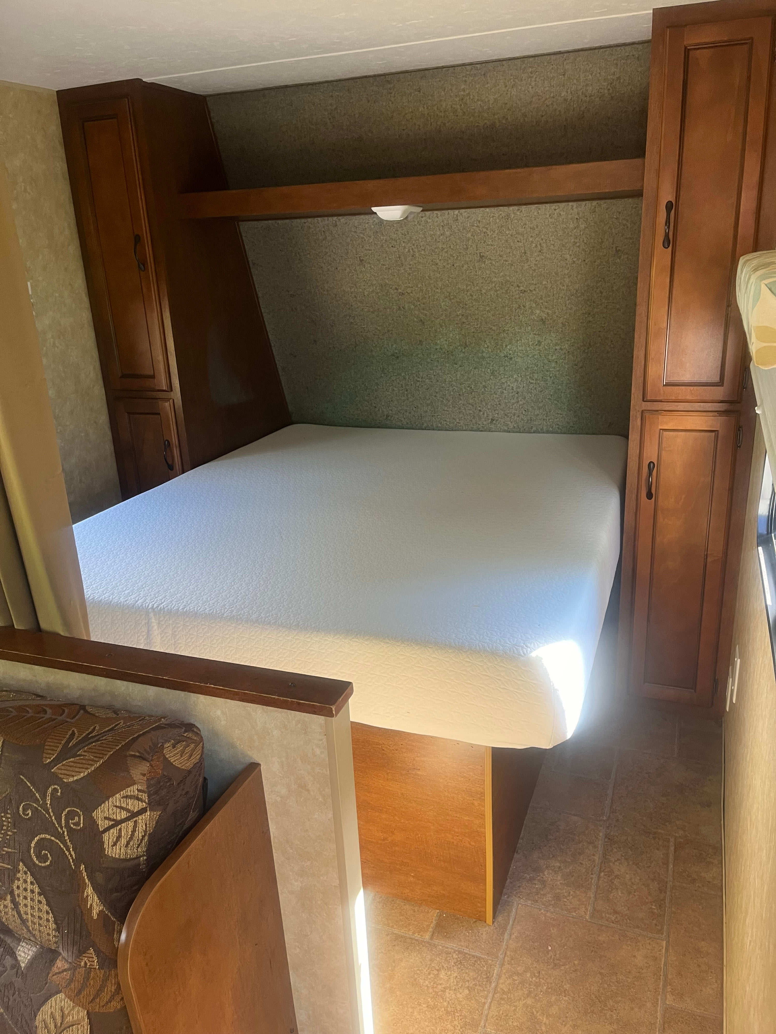 Queen bed foam mattress with storage underneath and a clothes closet on either side. Forest River Coachmen Catalina Santara 2012