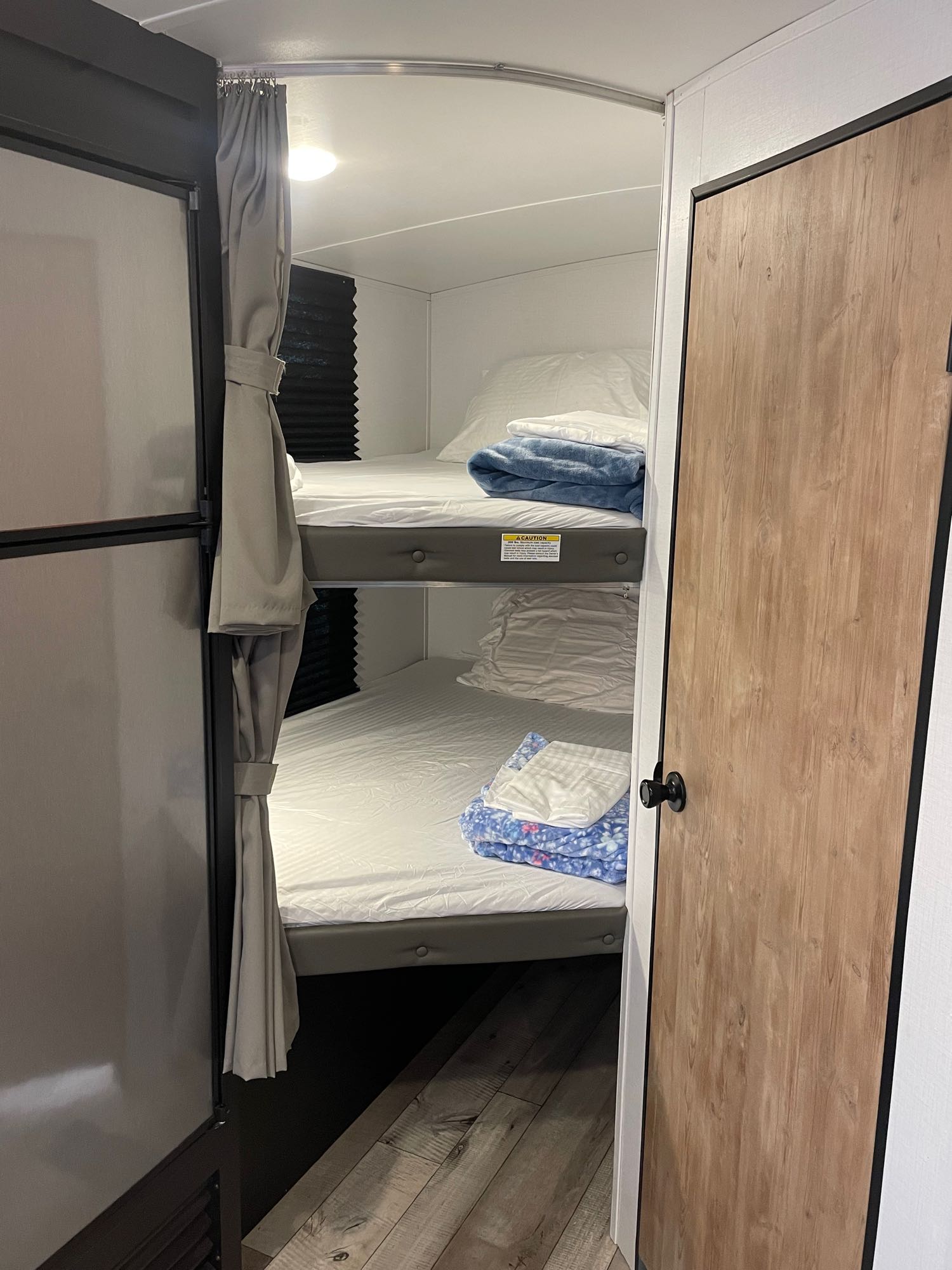 Compact RV rental interior featuring cozy bunk beds with privacy curtains, ideal for family travel.. Keystone RV Springdale 2022