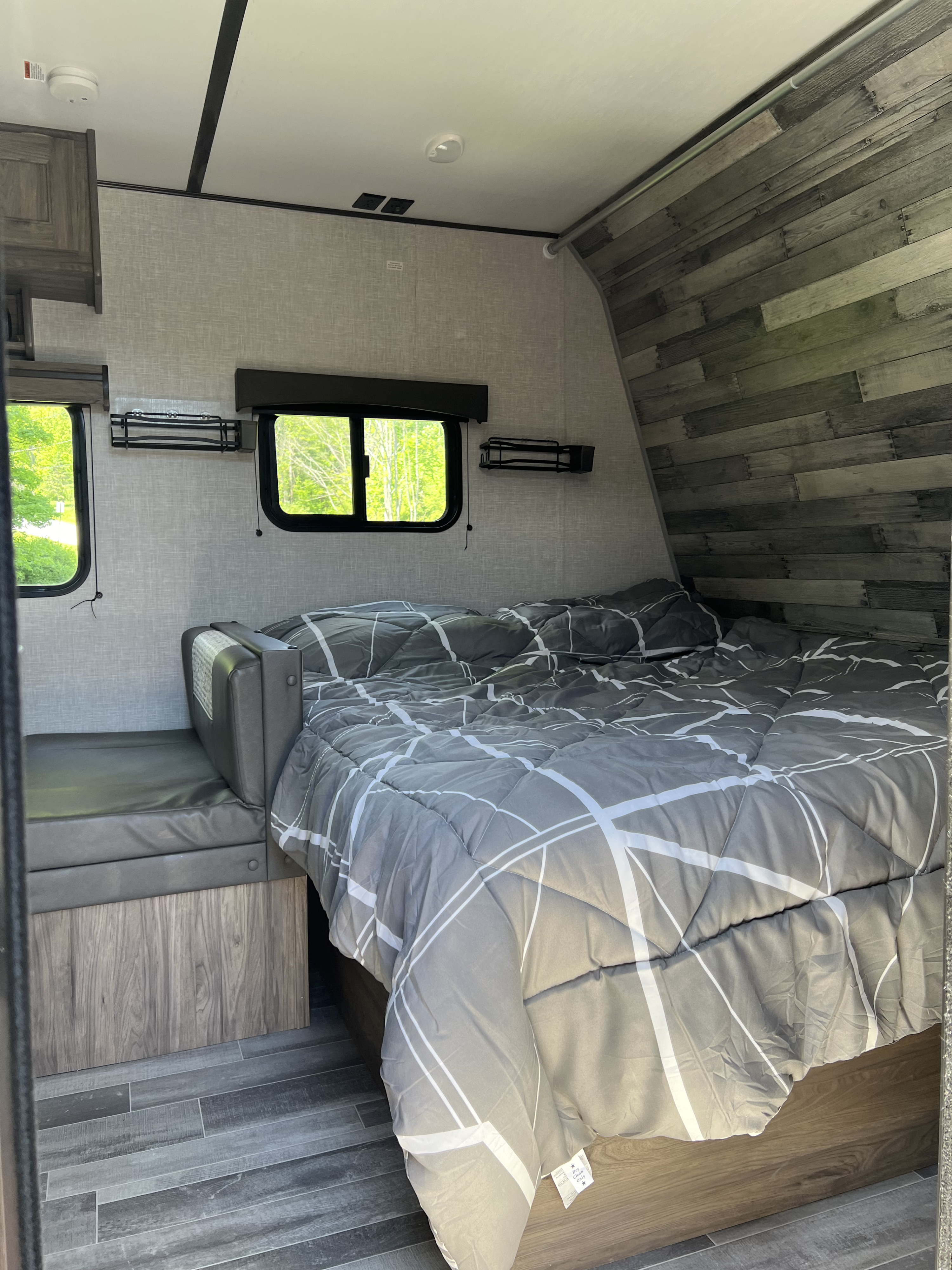 Comfy RV rental bedroom: modern gray bed, bright windows, and a cozy dinette. Ideal for travel adventures.. Crossroads RV Zinger Lite 2022