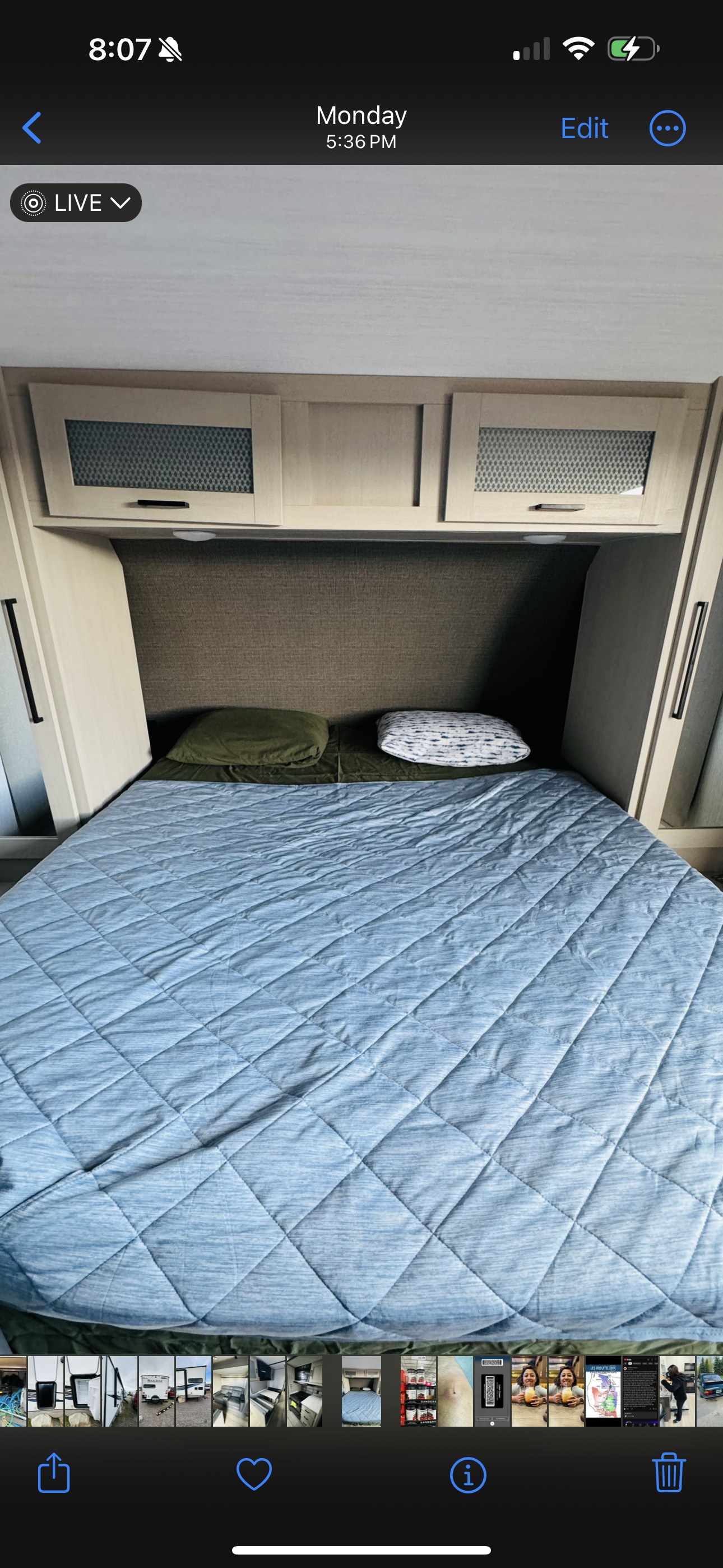 Inside an RV rental: a compact bedroom with a quilted blue bed, two pillows, and light-colored overhead cabinets.. Forest River Salem Hemisphere HL 2023