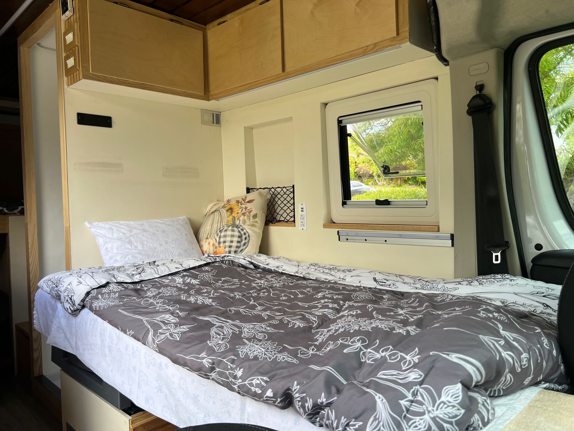 RV rental interior featuring a comfy bed, overhead cabinets, and a window to the outdoors.. Ram promaster 2500 2017