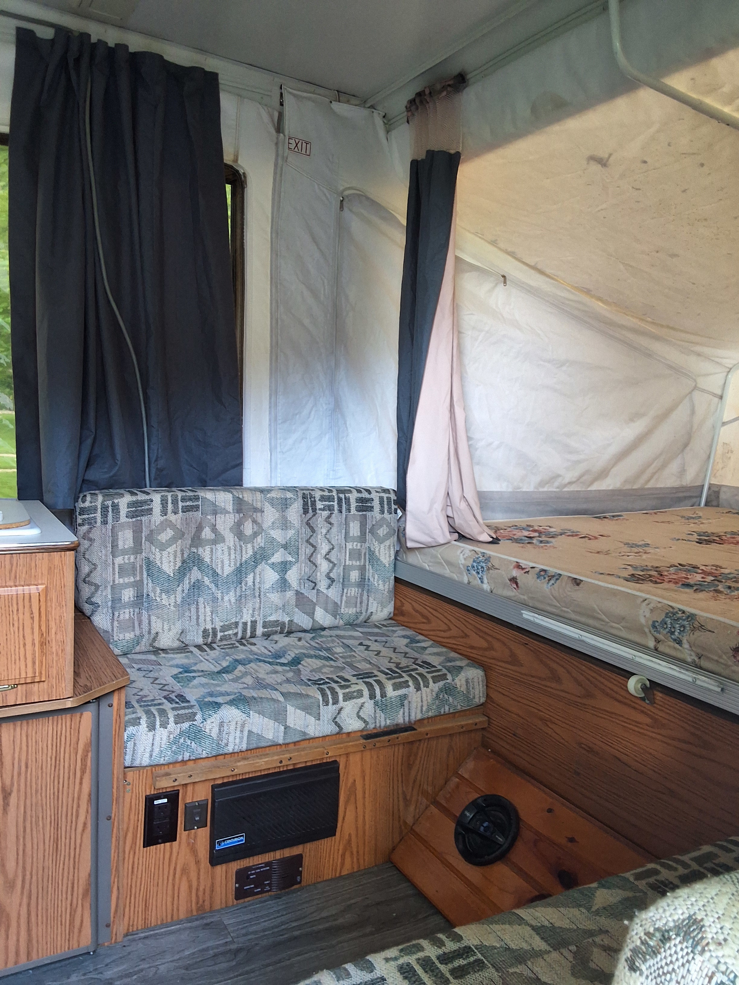 Cozy rv rental interior: pop-up camper with dinette, floral bed, canvas walls, and dark curtains.. Rockwood Other 2002