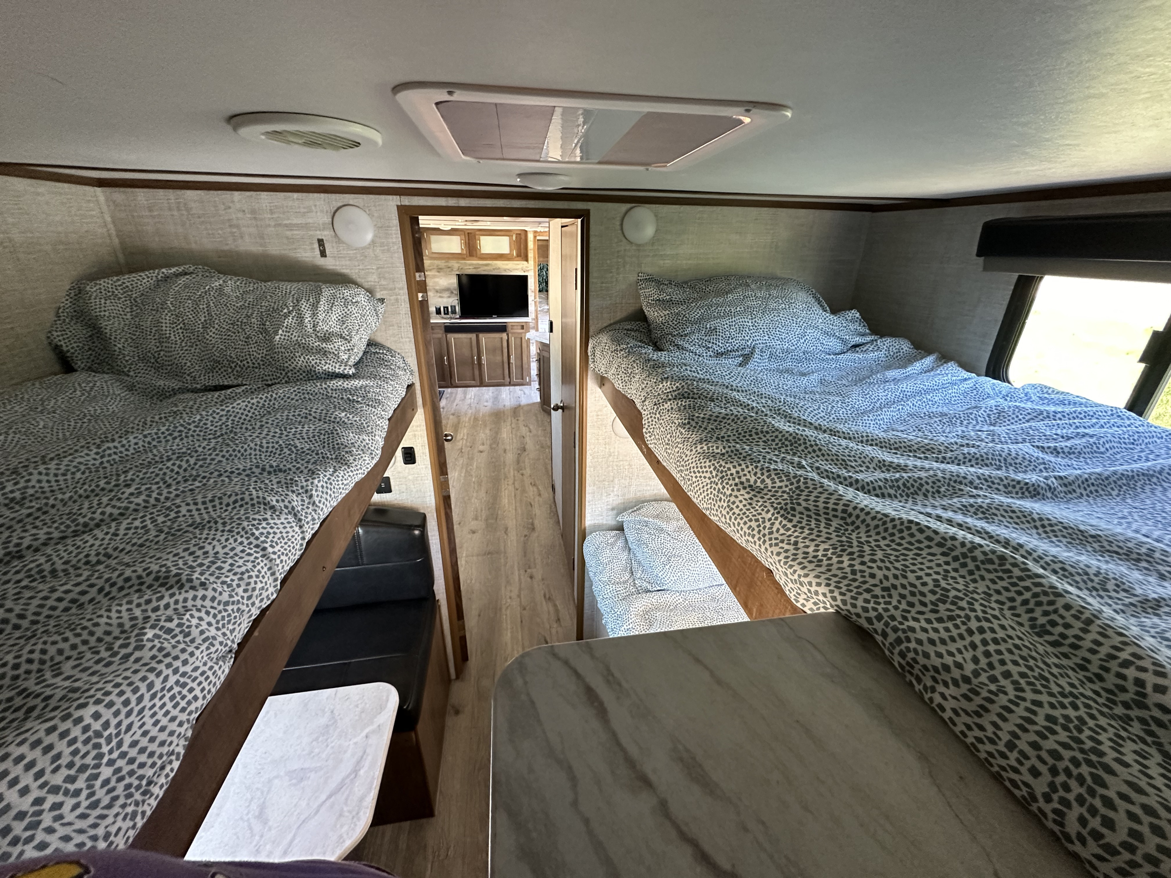 RV rental interior showing comfortable bunk beds with patterned linens, a dinette, and living space.. Gulf Stream Envision 2020