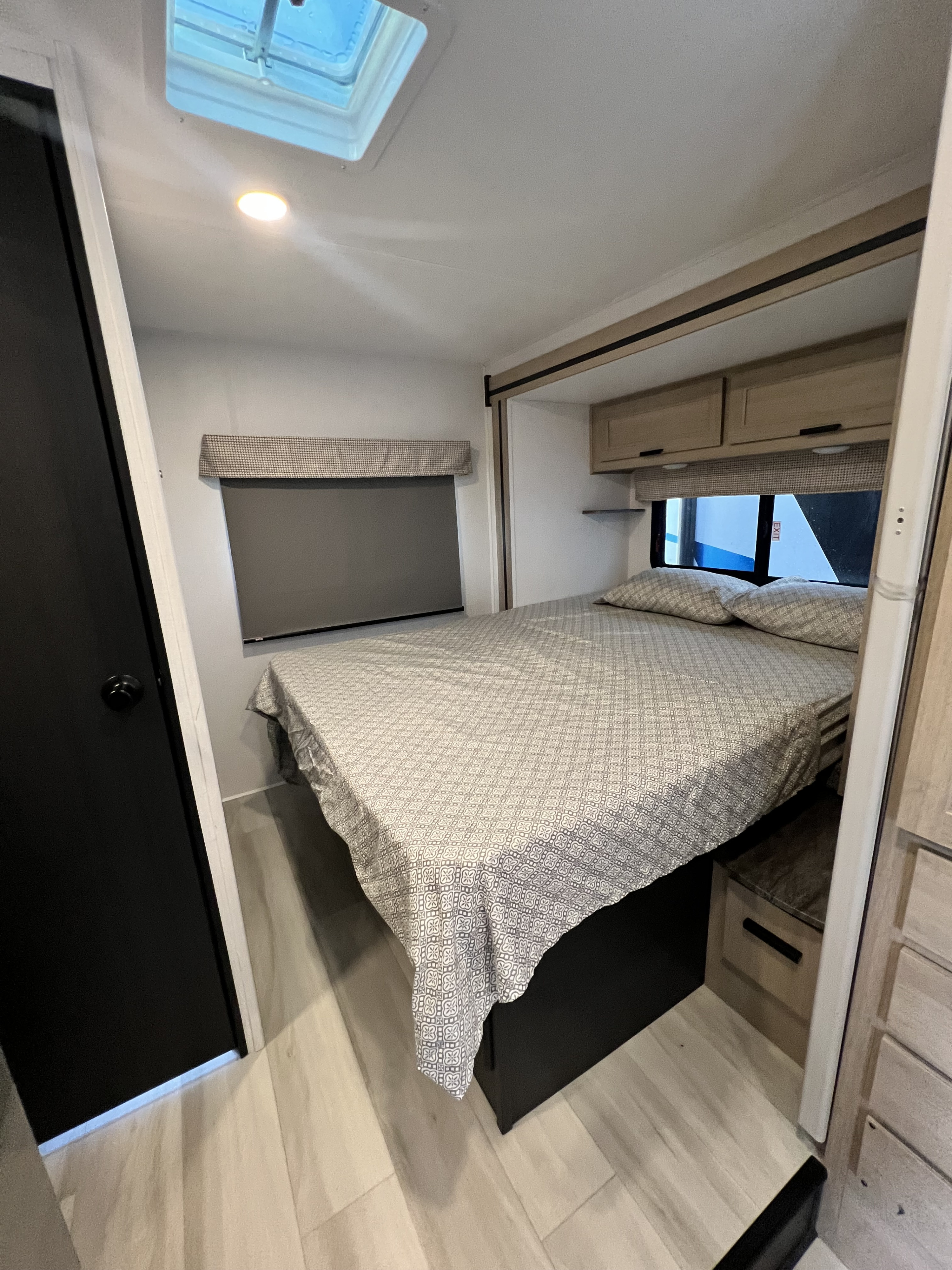 Step into a modern RV rental bedroom featuring a bed with patterned bedding, overhead storage, and a ceiling skylight.. Forest River Sunseeker 2025