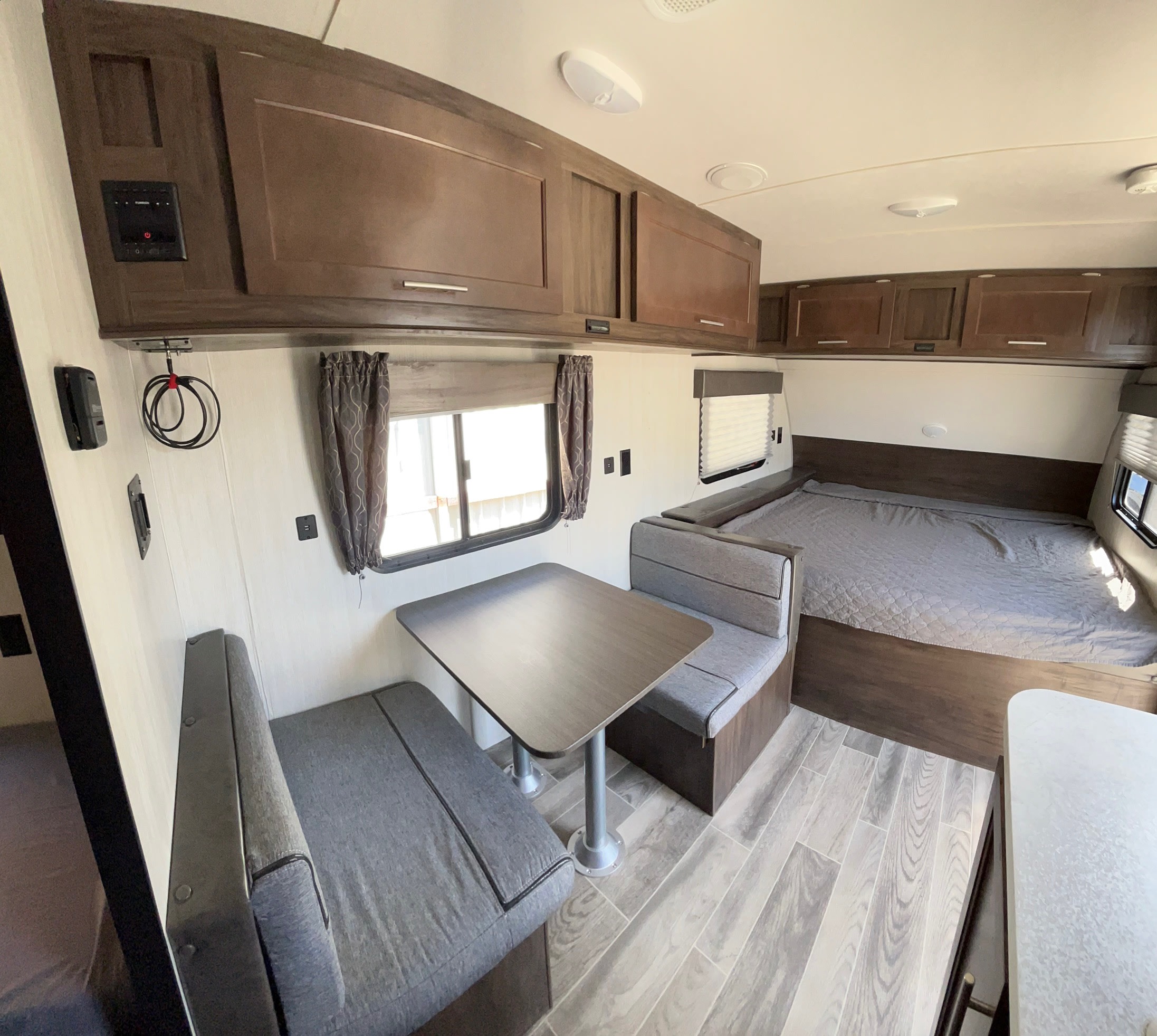 Spacious RV rental interior showcasing a cozy dinette, modern overhead cabinets, and a comfortable bed, perfect for travel.. Forest River Cherokee Wolf Pup 2020