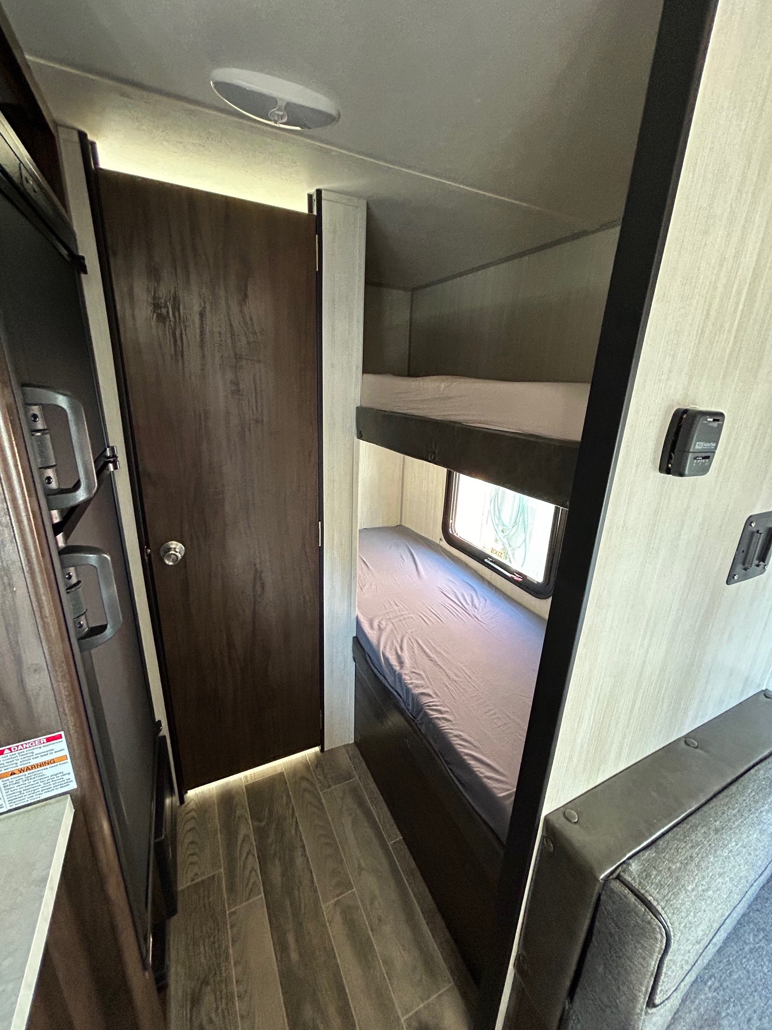 Inside an RV rental: view of bunk beds, a private door, and kitchen space, highlighting compact living and travel comfort.. Forest River Cherokee Wolf Pup 2020