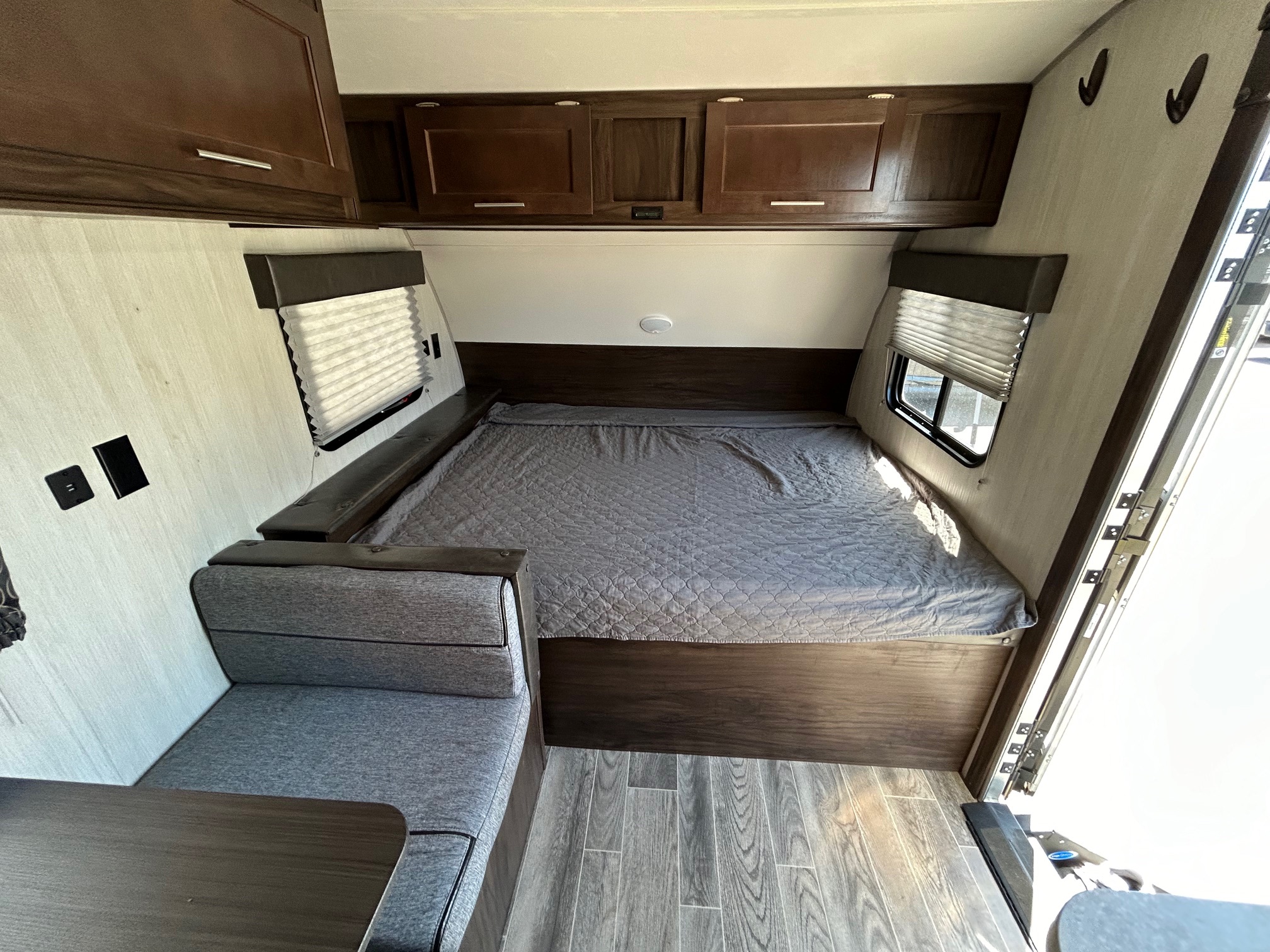 Inside an RV rental: a compact sleeping and seating area with dark wood cabinets & modern gray finishes.. Forest River Cherokee Wolf Pup 2020