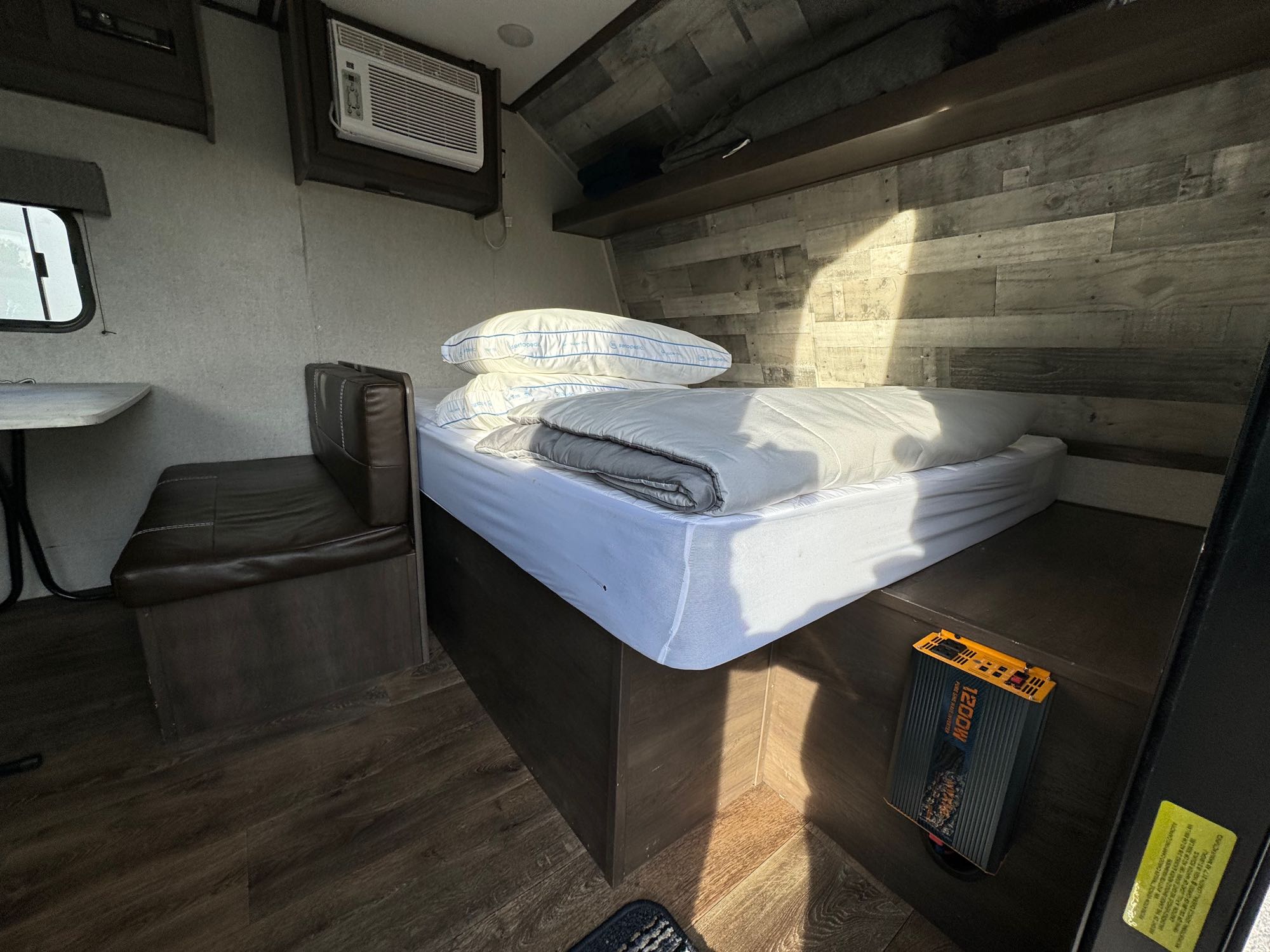 Cozy RV rental interior featuring a comfortable bed, dinette, AC unit, and a visible 1200W inverter, ideal for on-the-go living.. Dutchmen Coleman Lantern LT 2021