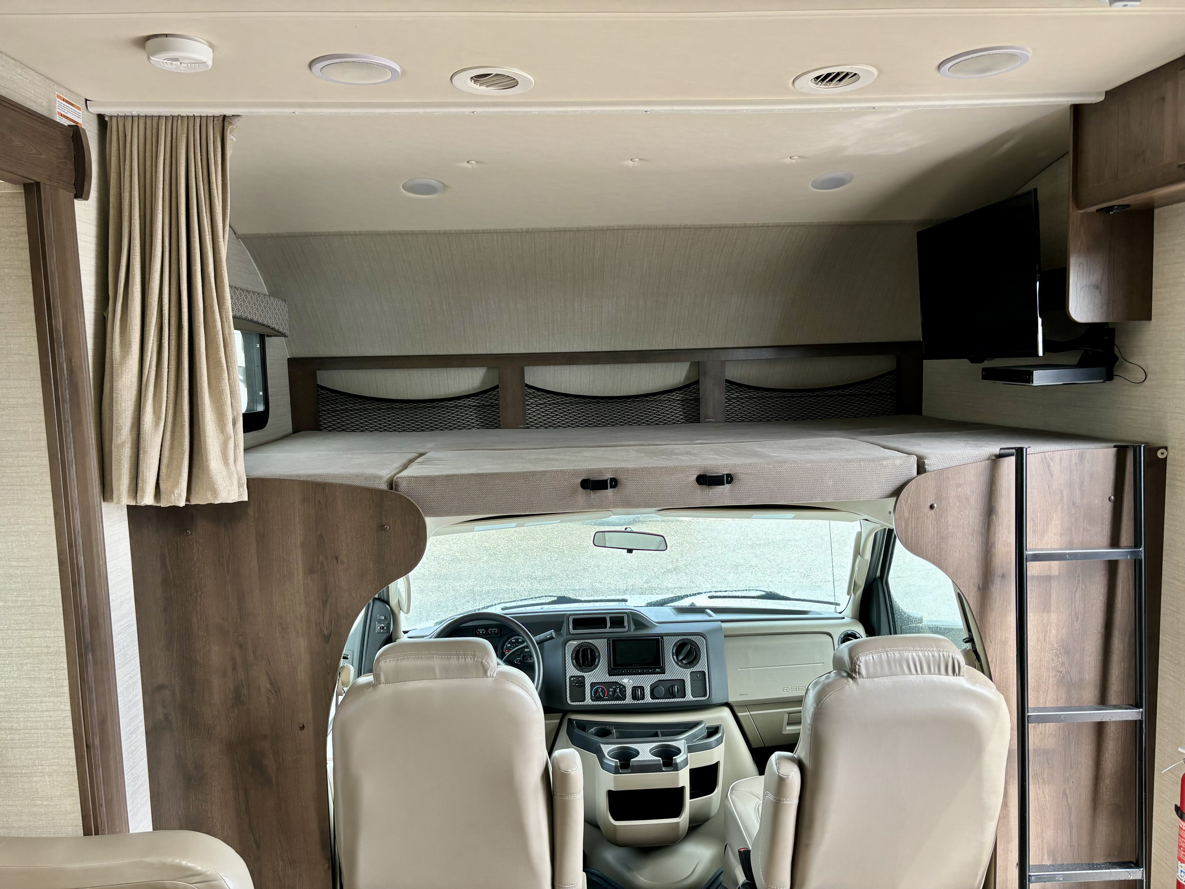 Spacious RV rental interior with over-cab bunk bed, front cockpit, and entertainment system.. Jayco Greyhawk 2018