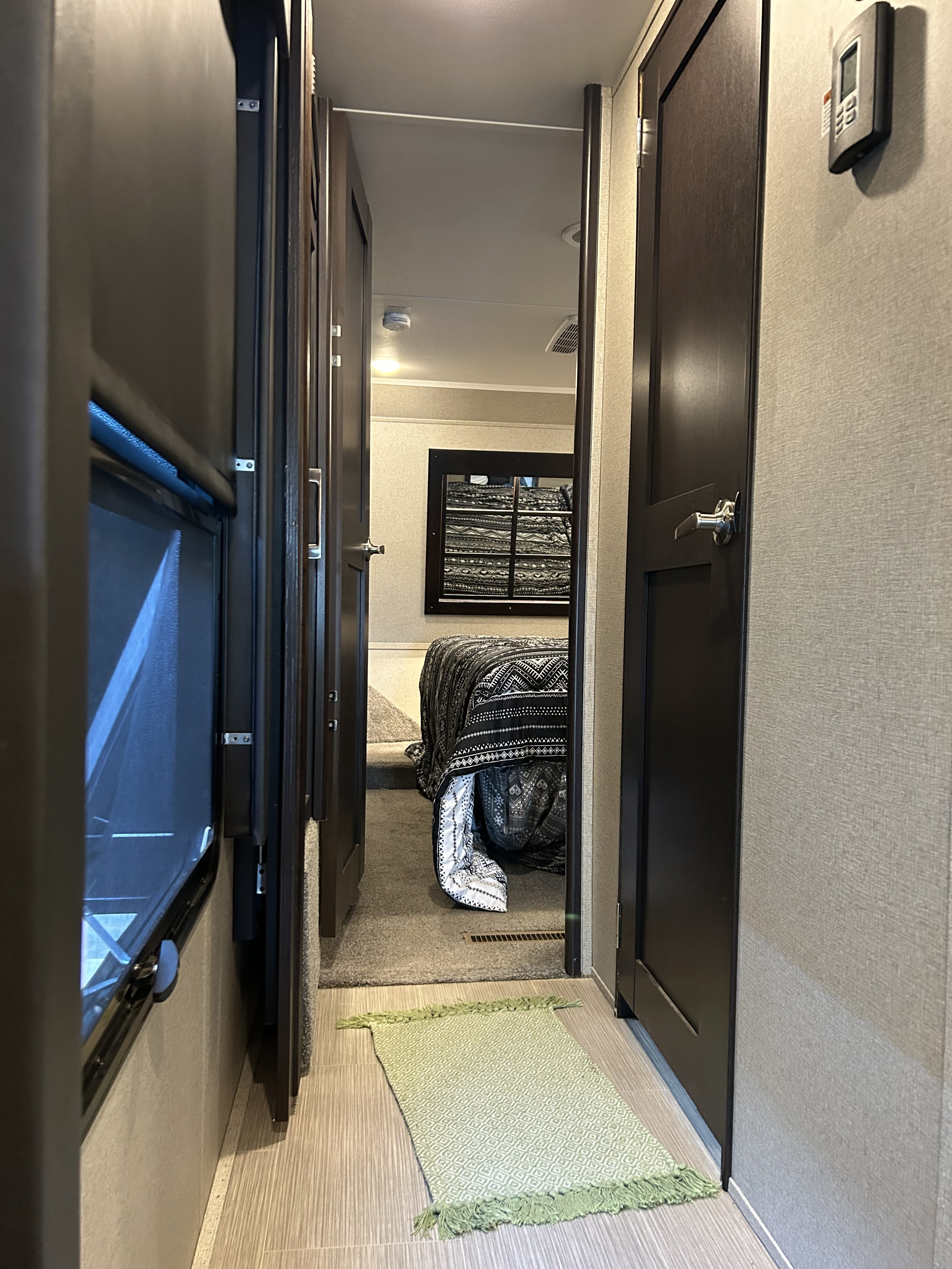 Step into comfort with this modern RV rental! Hallway view to a cozy bedroom with patterned bedding and wall art.. Raptor Raptor 2017