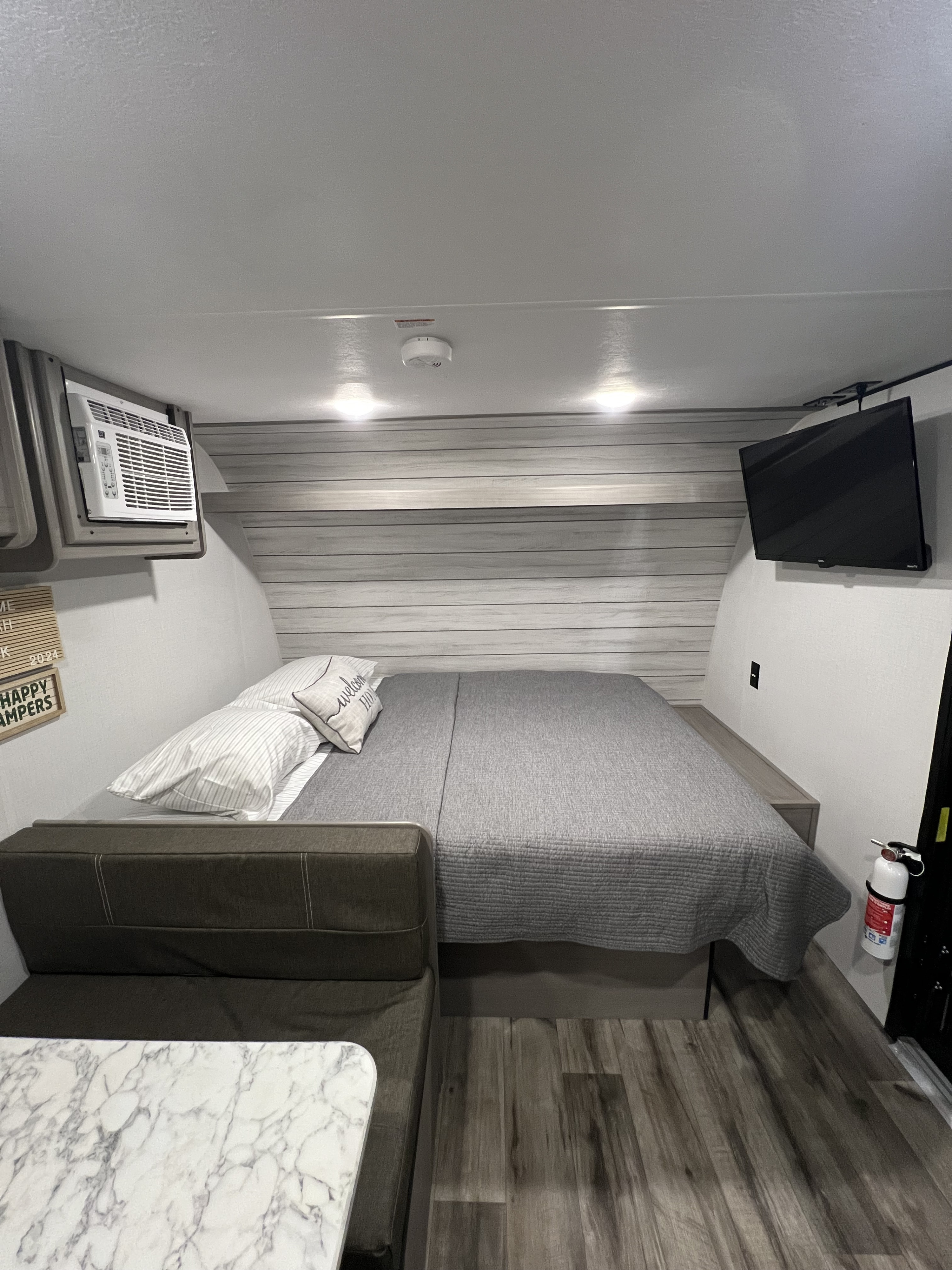 Explore this modern RV rental interior: spacious bed, seating/dinette area, AC, and TV. Perfect for your next adventure!. Coleman Lantern 17B 2024