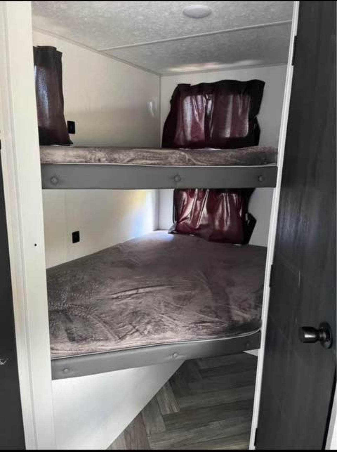 RV rental interior: two stacked bunk beds with gray bedding and dark privacy covers, great for extra sleeping.. Forest River Wildwood FSX 2023