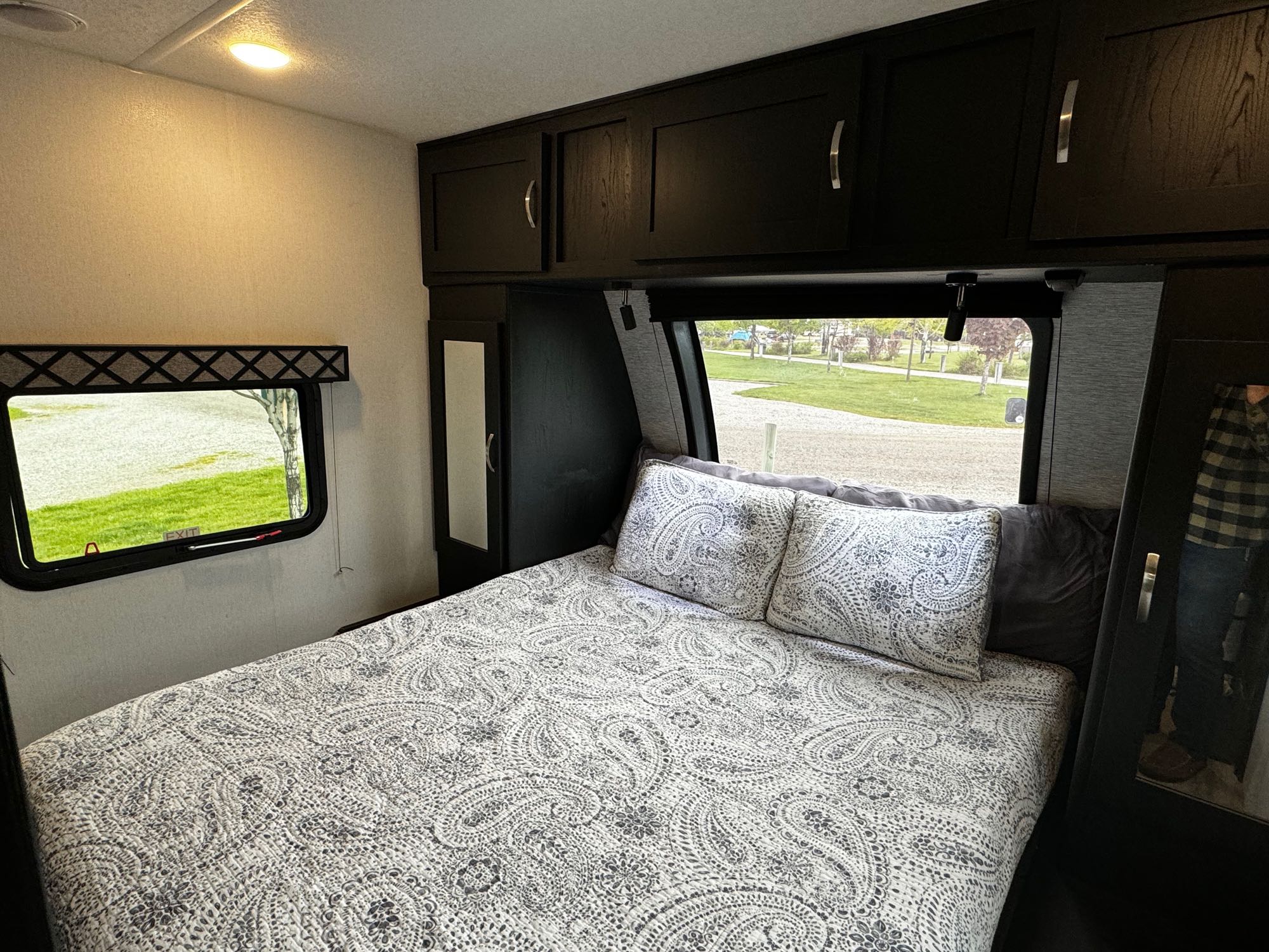 Comfortable RV rental bedroom with patterned bedding, overhead cabinets, and a scenic window view.. Forest River Coachmen Freedom Express Ultra Lite 2022