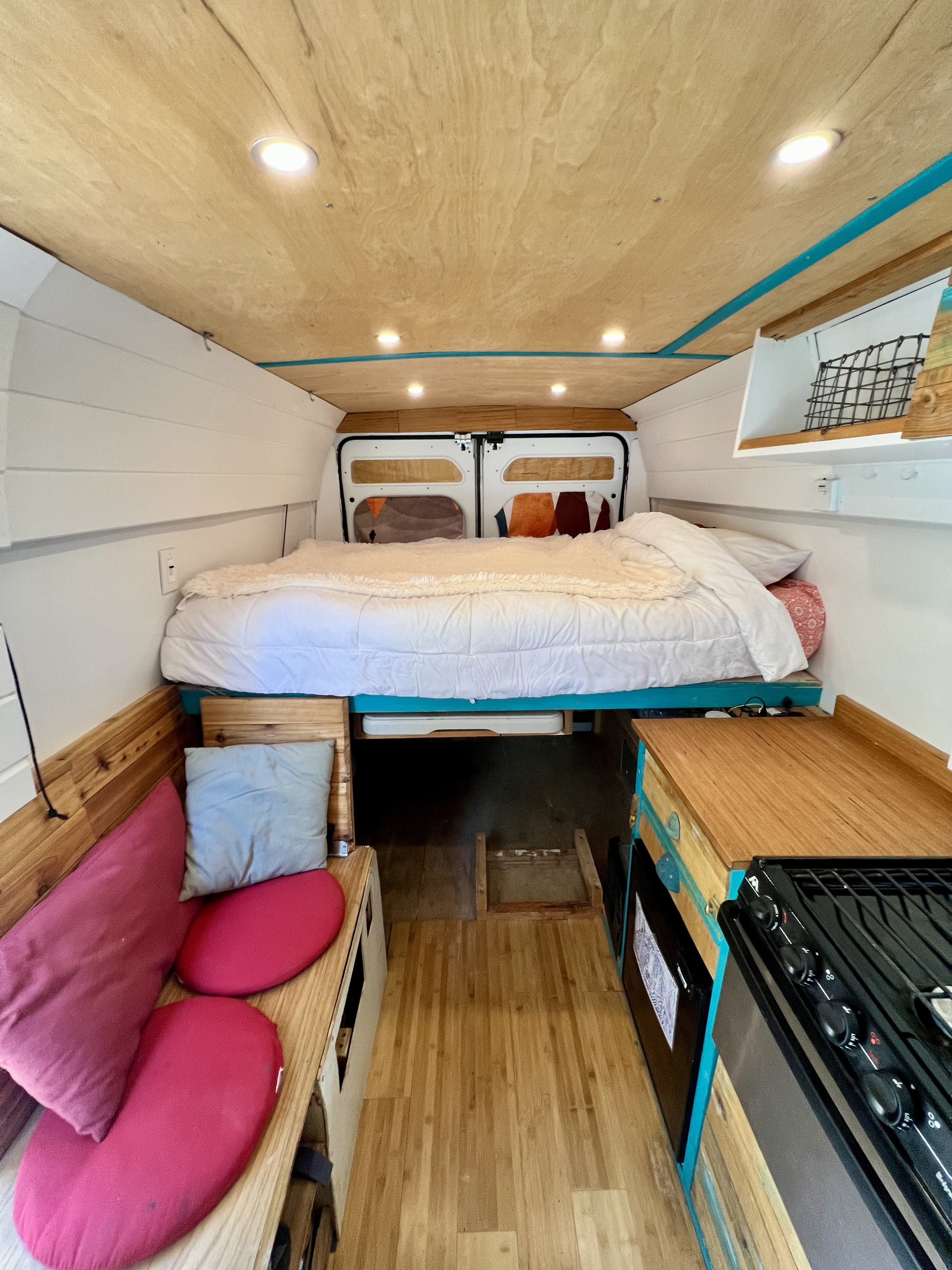 Camper van interior for your next RV rental. Features a cozy bed, kitchen, & natural wood finishes.. Dodge Promaster 2500 159 WB 2017