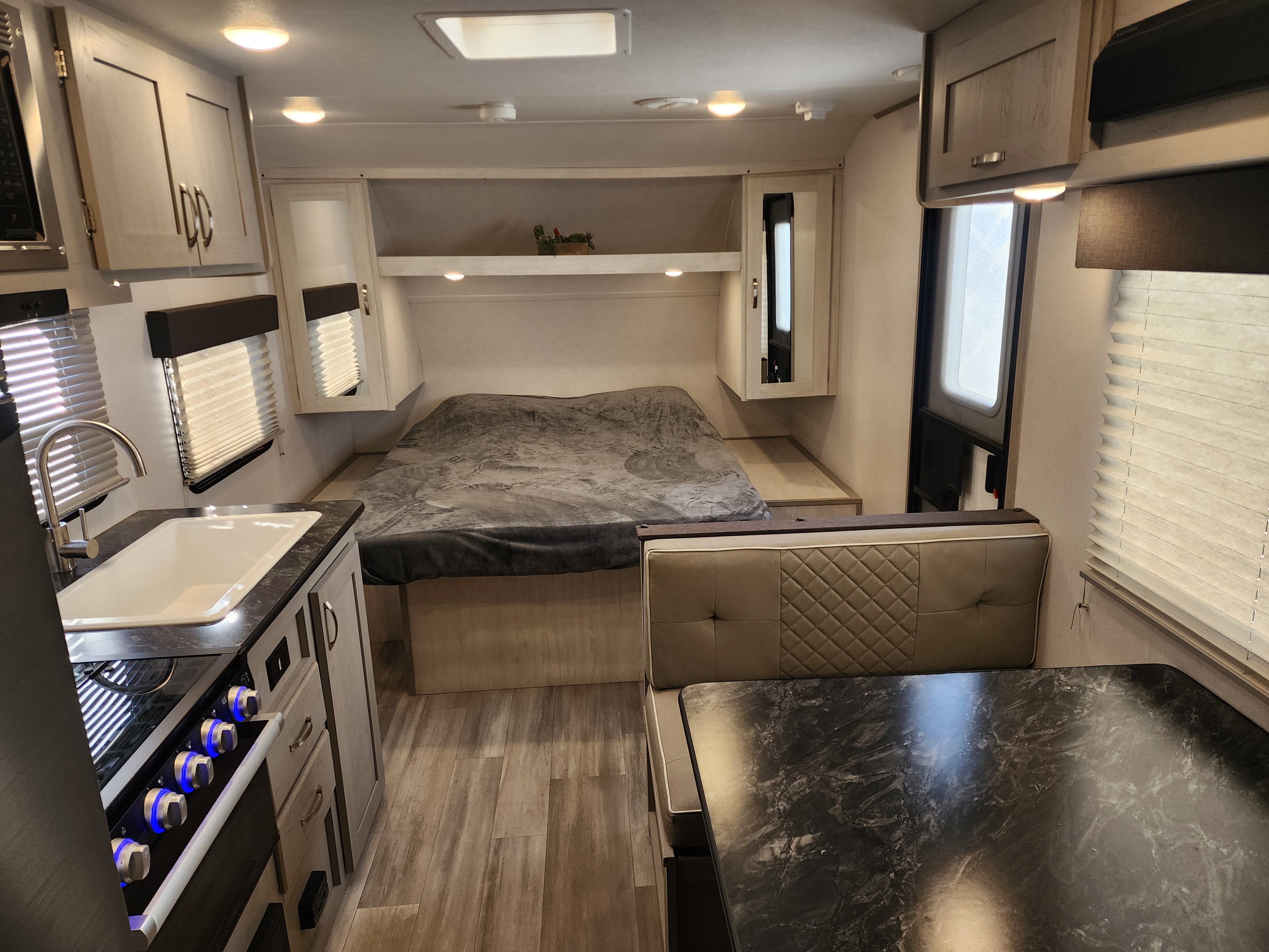 Step inside this clean rv rental: a modern interior with kitchen (sink/stove), cozy bed, and dinette. Wood-look flooring & light cabinets.. Primetime Tracer 2022