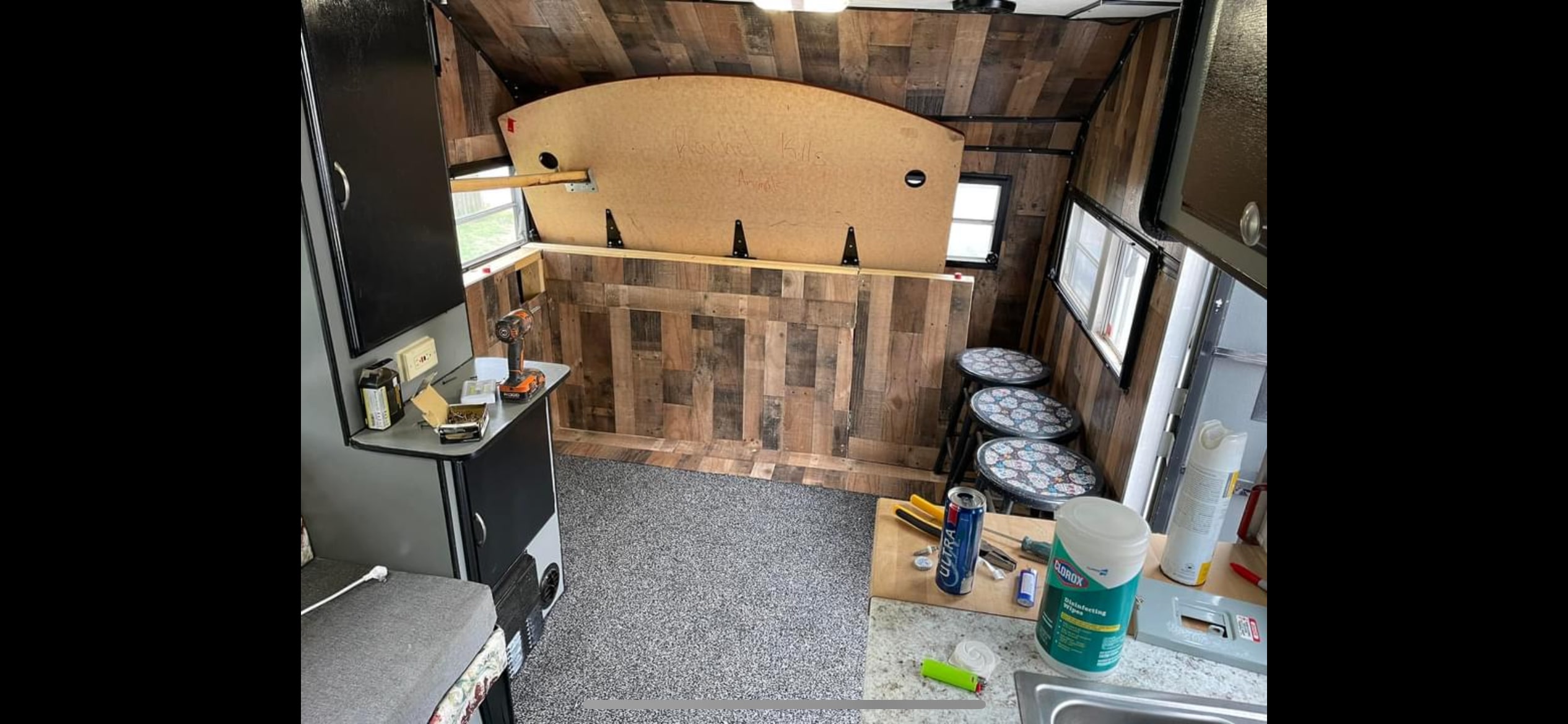 Wood-paneled RV rental interior with lift-up bed, compact kitchen, and bar stools. Cozy and adventure-ready.. Sunline T2251 1985