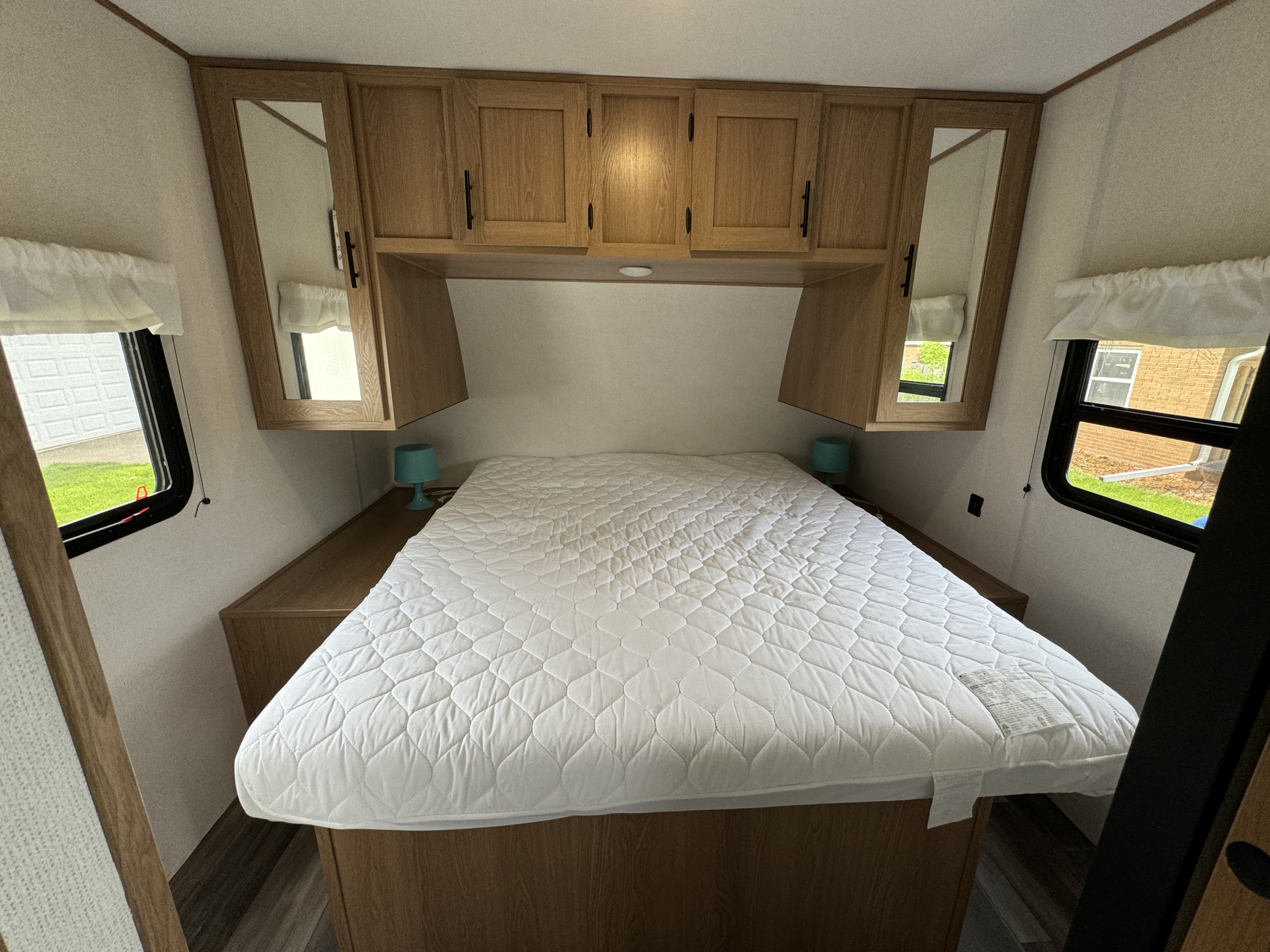 Clean RV rental bedroom with a queen bed, overhead cabinets with mirrors, and side windows for natural light.. Prime Time Avenger 2022